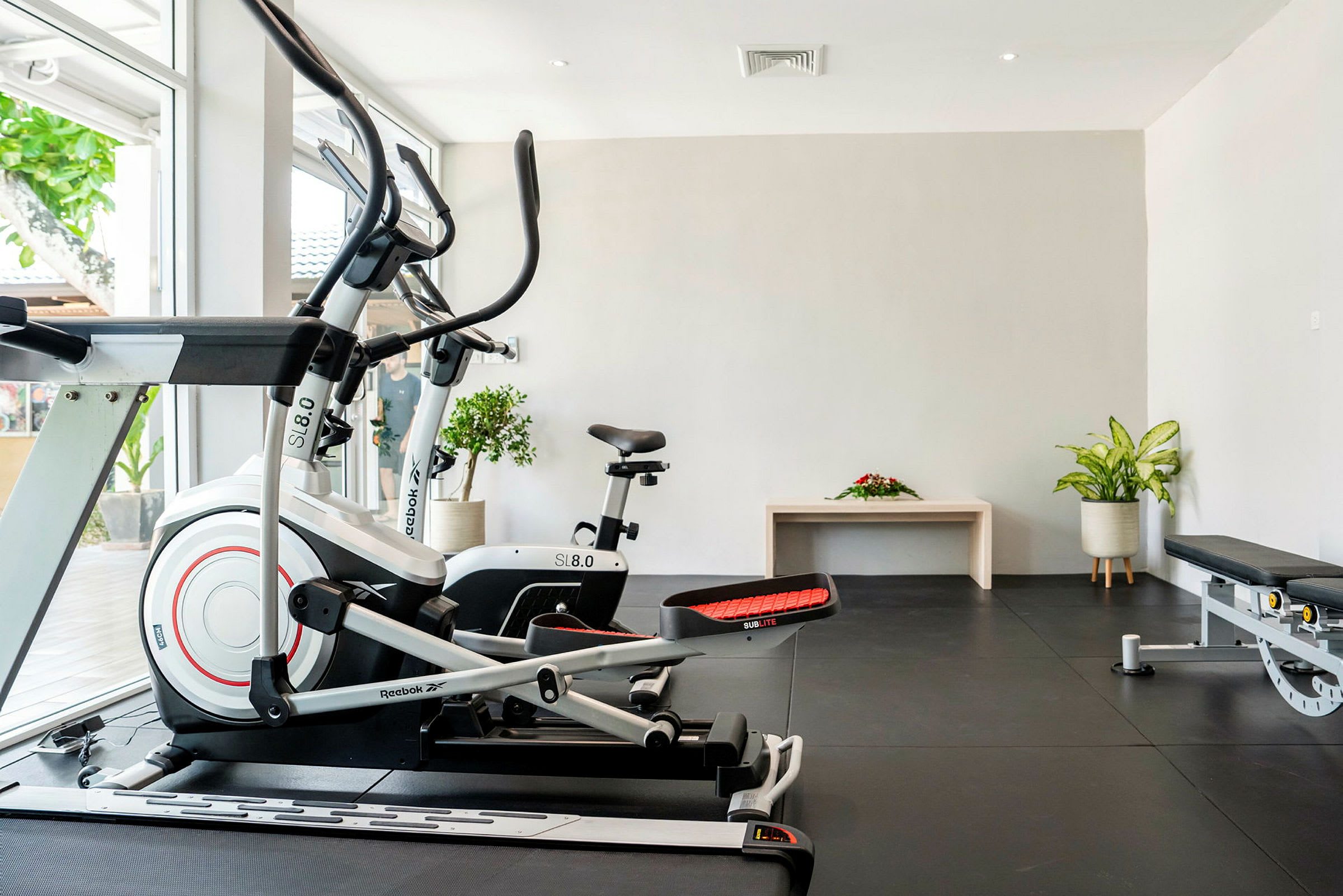 Gym med træningsmaskiner og planter. (AI-genereret tekst)