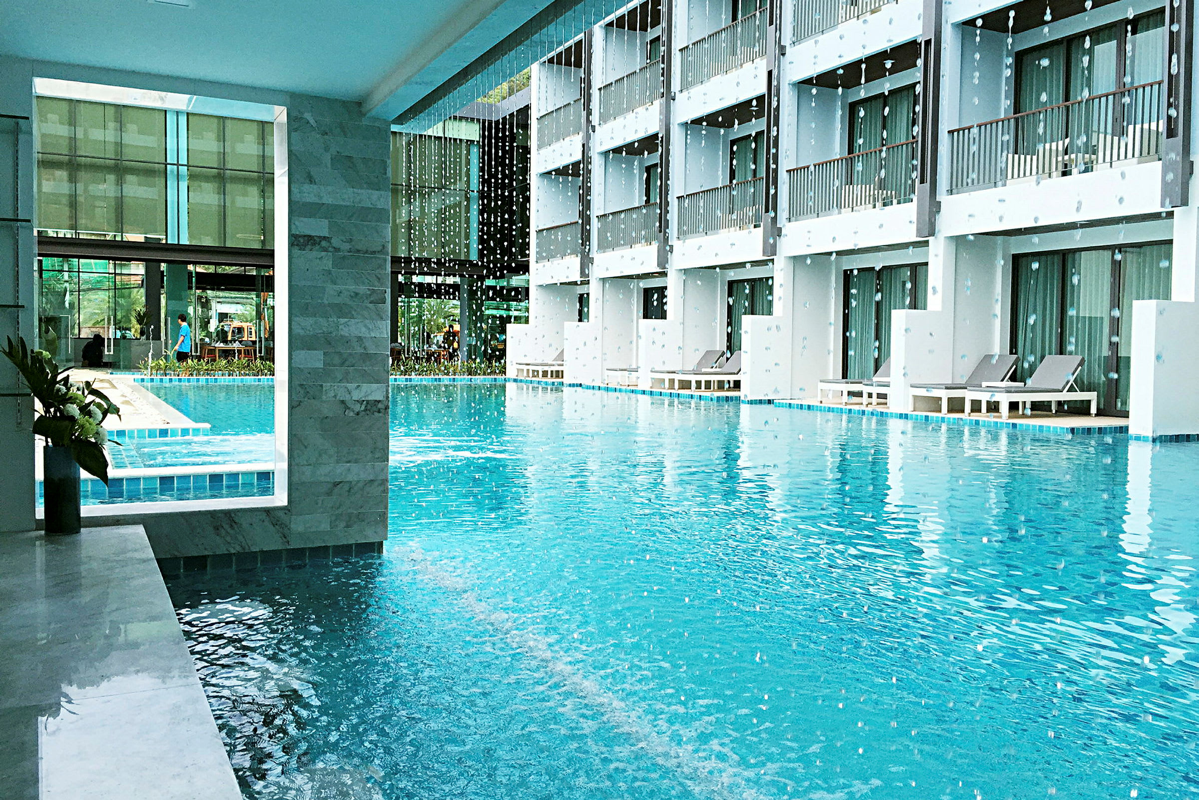 Udendørs pool ved hotel med liggestole og altaner. (AI-genereret tekst)