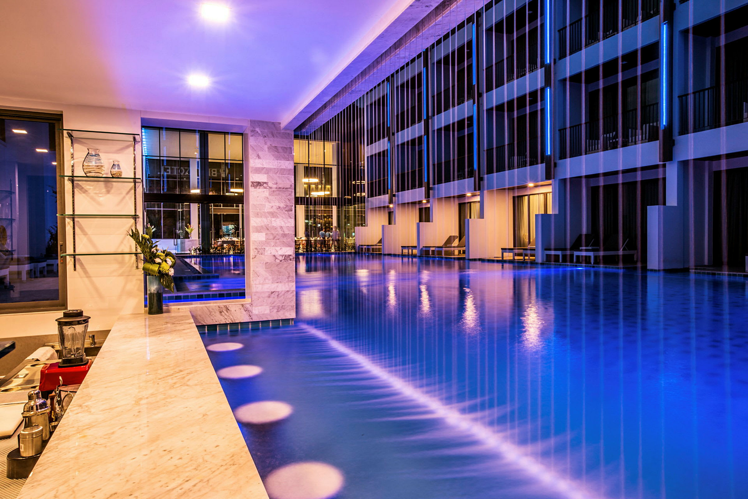 Billede af en moderne hotelpool med omgivende belysning og elegante møbler. (AI-genereret tekst)