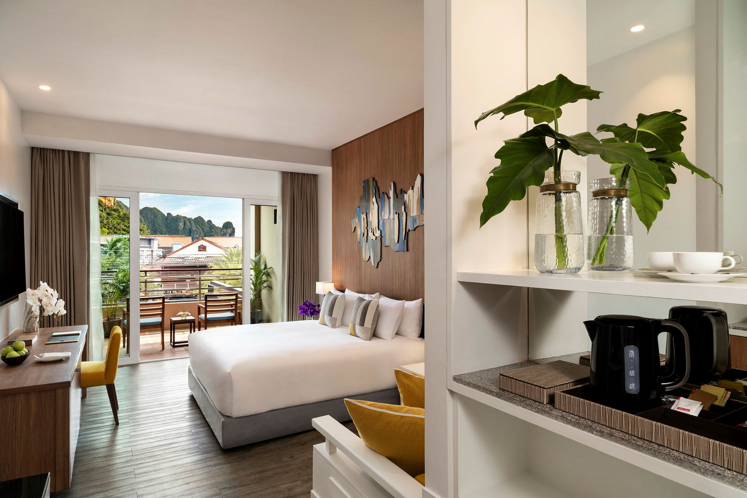 Et moderne hotelværelse med en behagelig seng, arbejdsområde og en balkon med udsigt over omgivelserne. (AI-genereret tekst)
