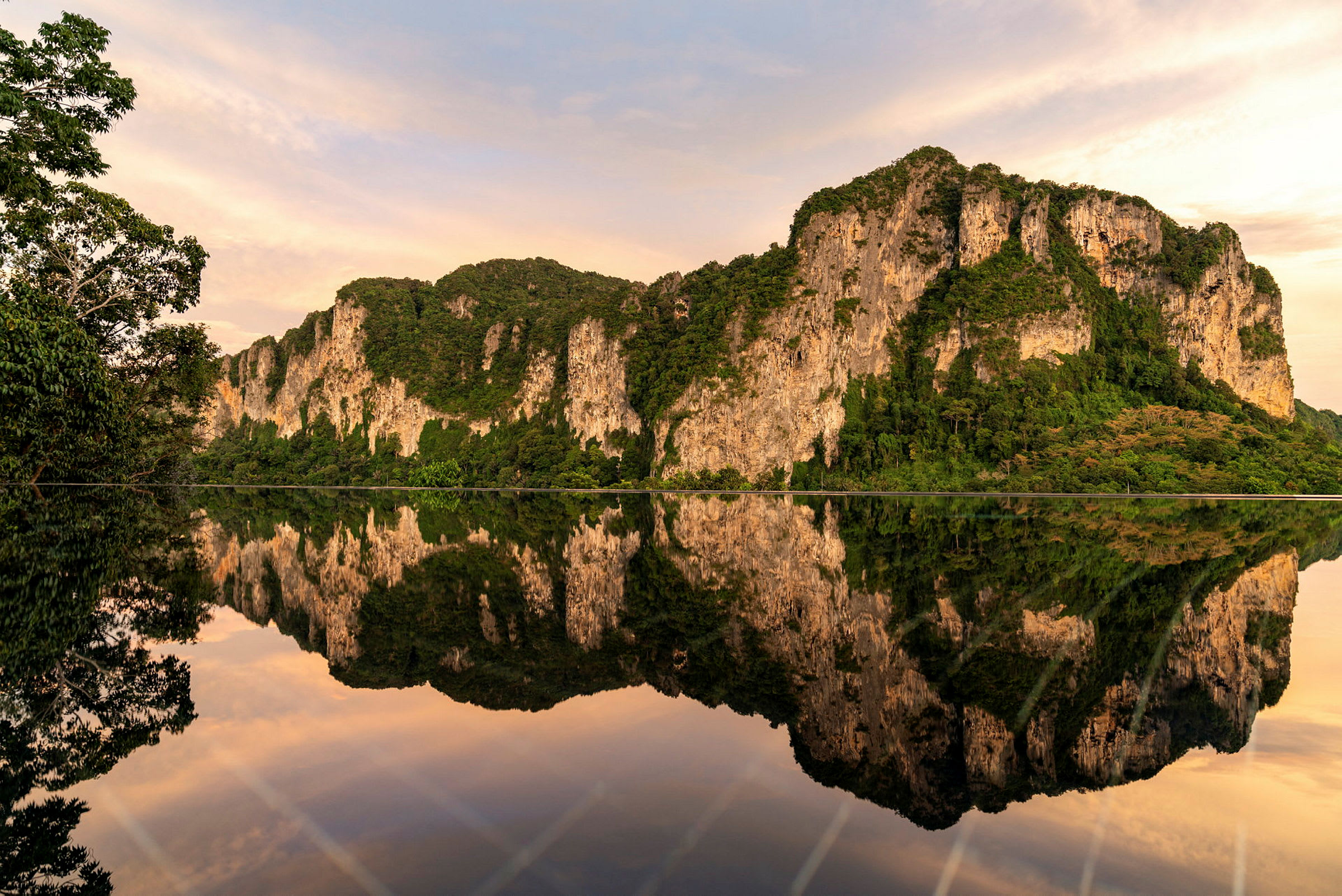 En udsigt over en spejlblank sø, der reflekterer de omkringliggende bjerge og grønninger under en overskyet himmel. (AI-genereret tekst)