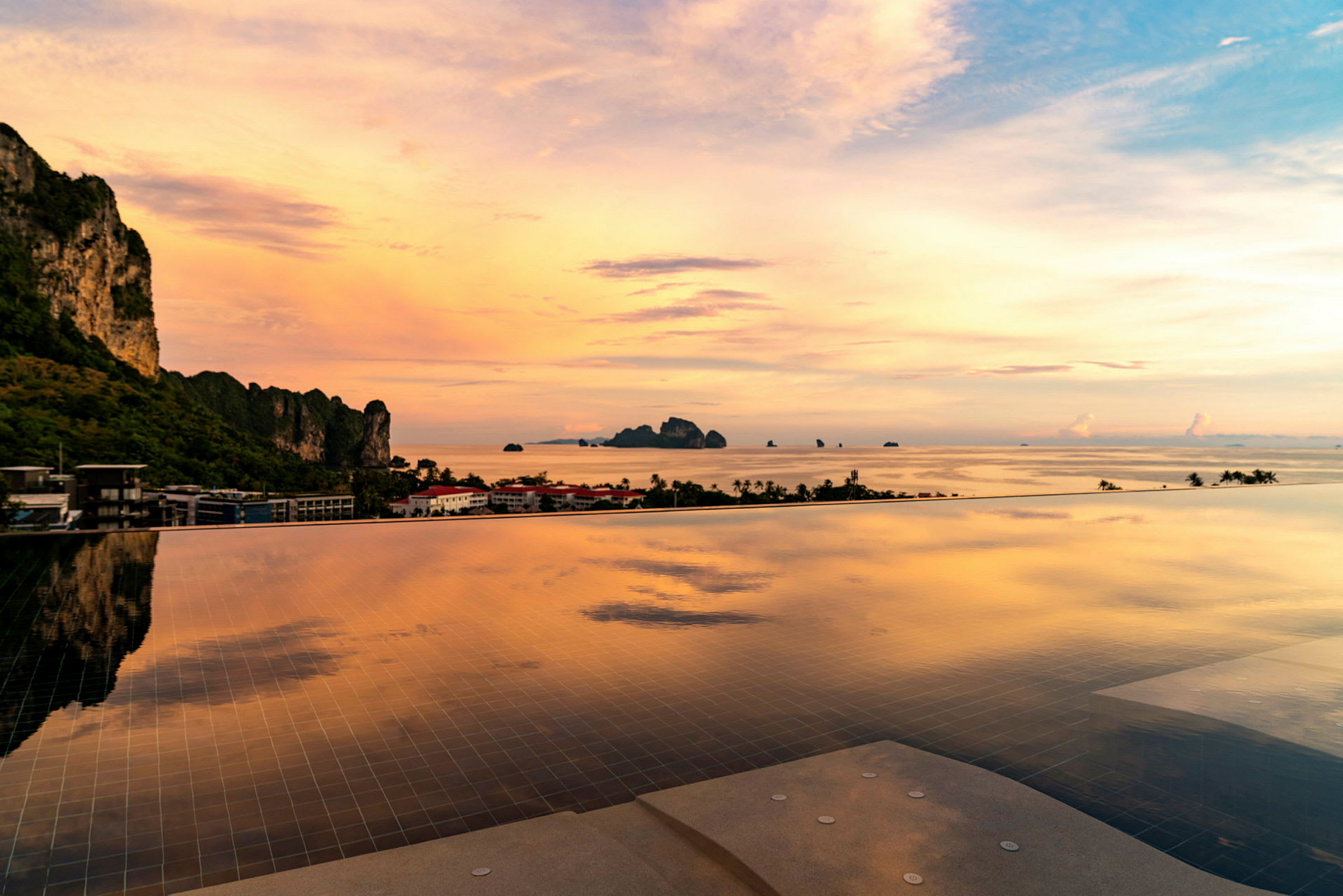 Infinitypool med udsigt over havet, himlen i orange og blå nuancer ved solnedgang. (AI-genereret tekst)