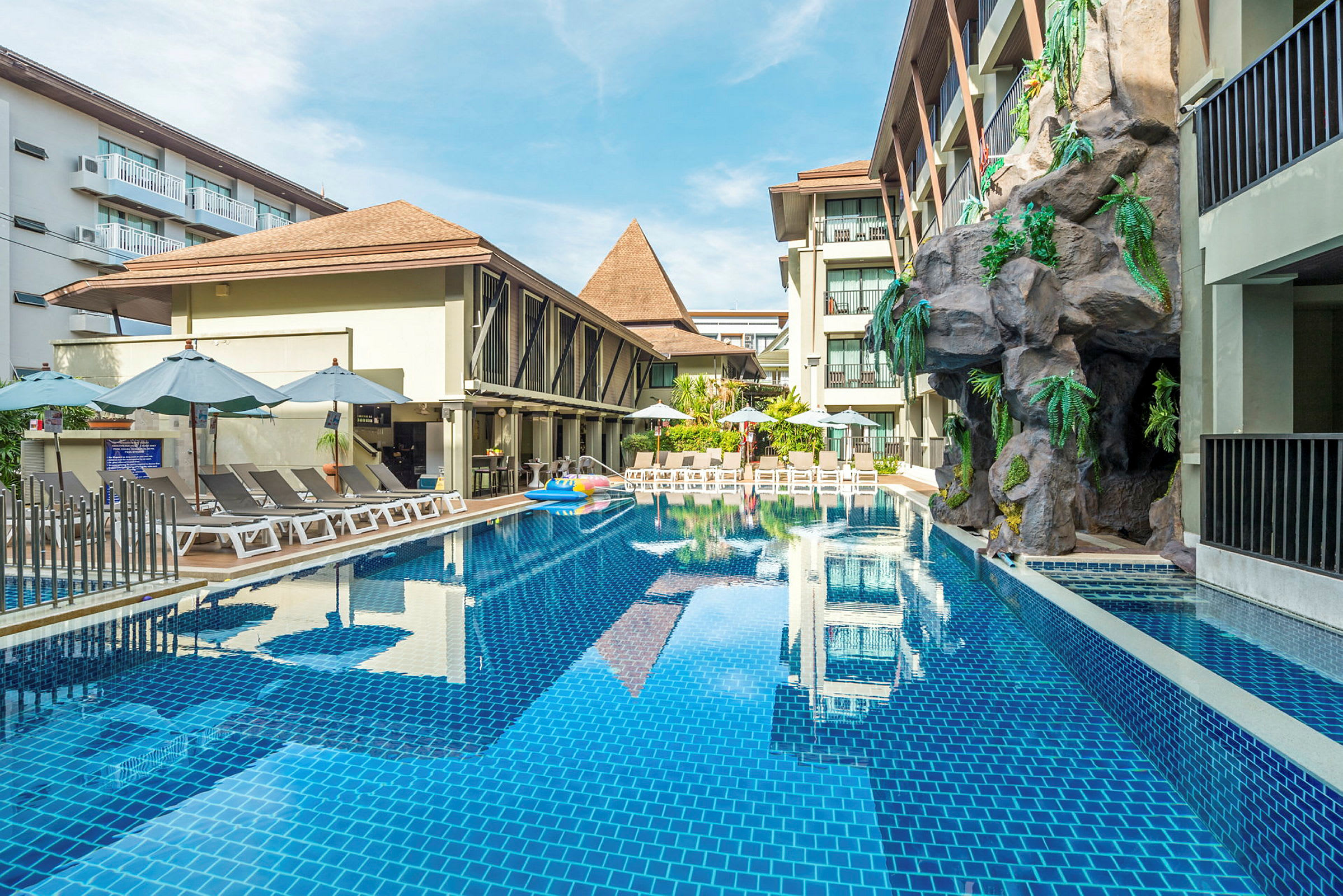 Udendørs pool ved et hotel med liggestole og parasoller. (AI-genereret tekst)