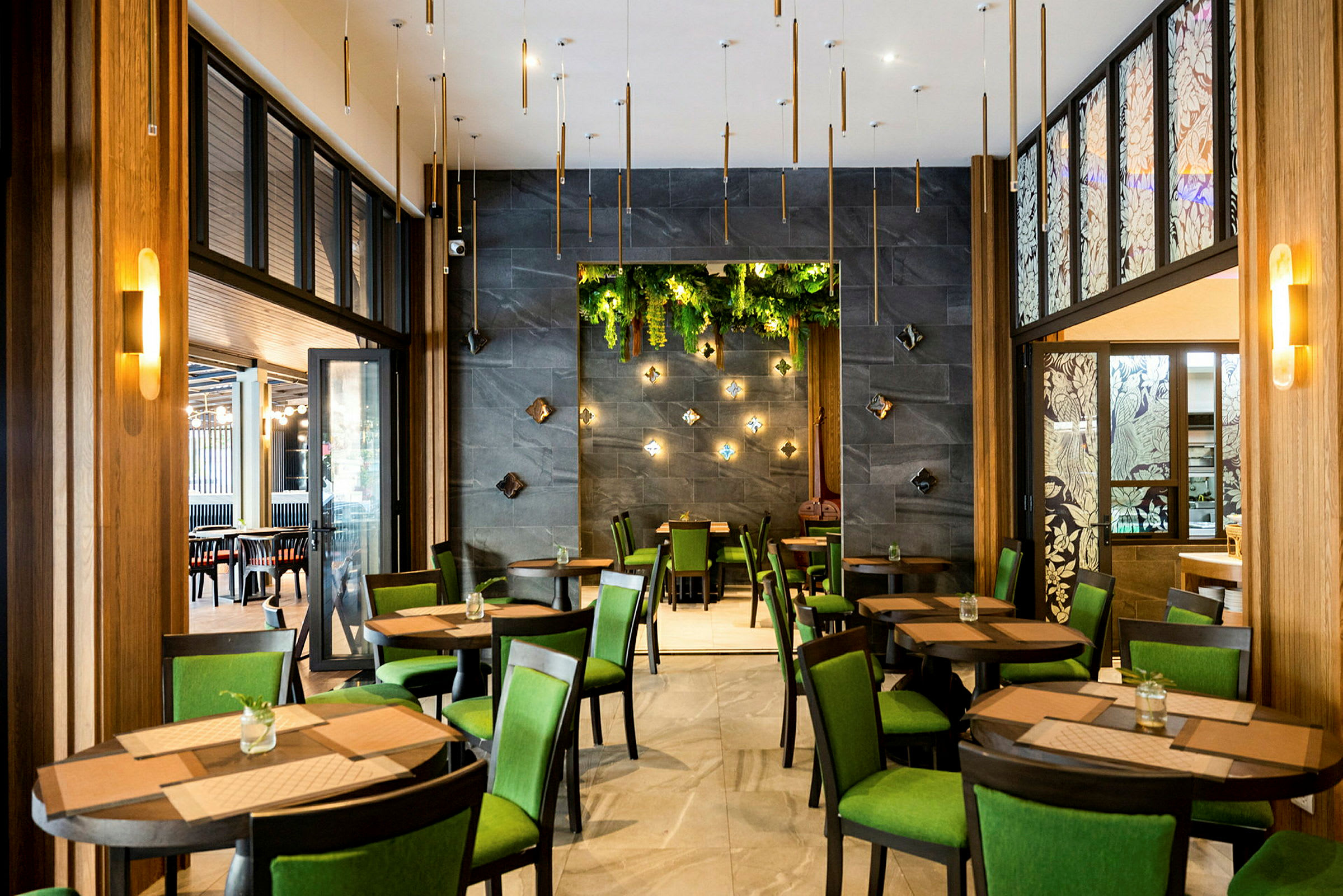 Restaurant med borde og stole, grønne detaljer og dekorative vægdetaljer. (AI-genereret tekst)