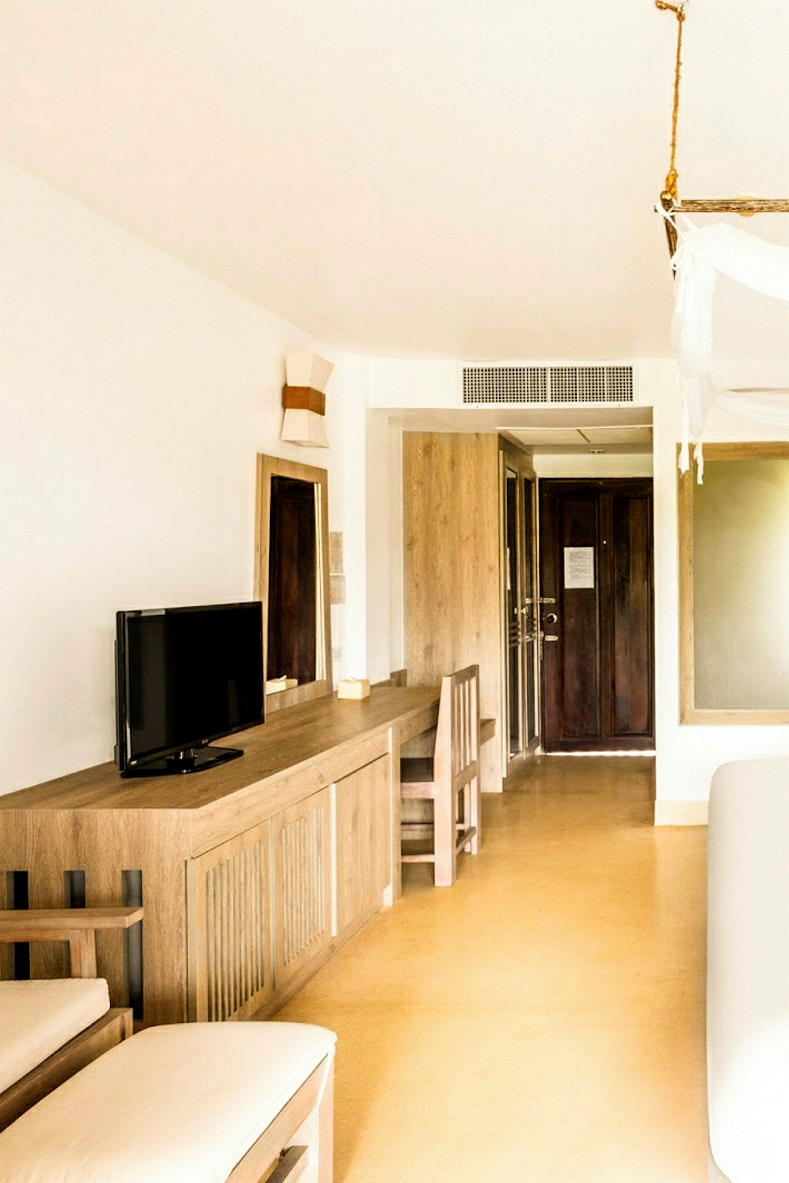 Et hotelværelse med minimalistisk indretning, herunder et skrivebord, en stol og et lille TV. (AI-genereret tekst)