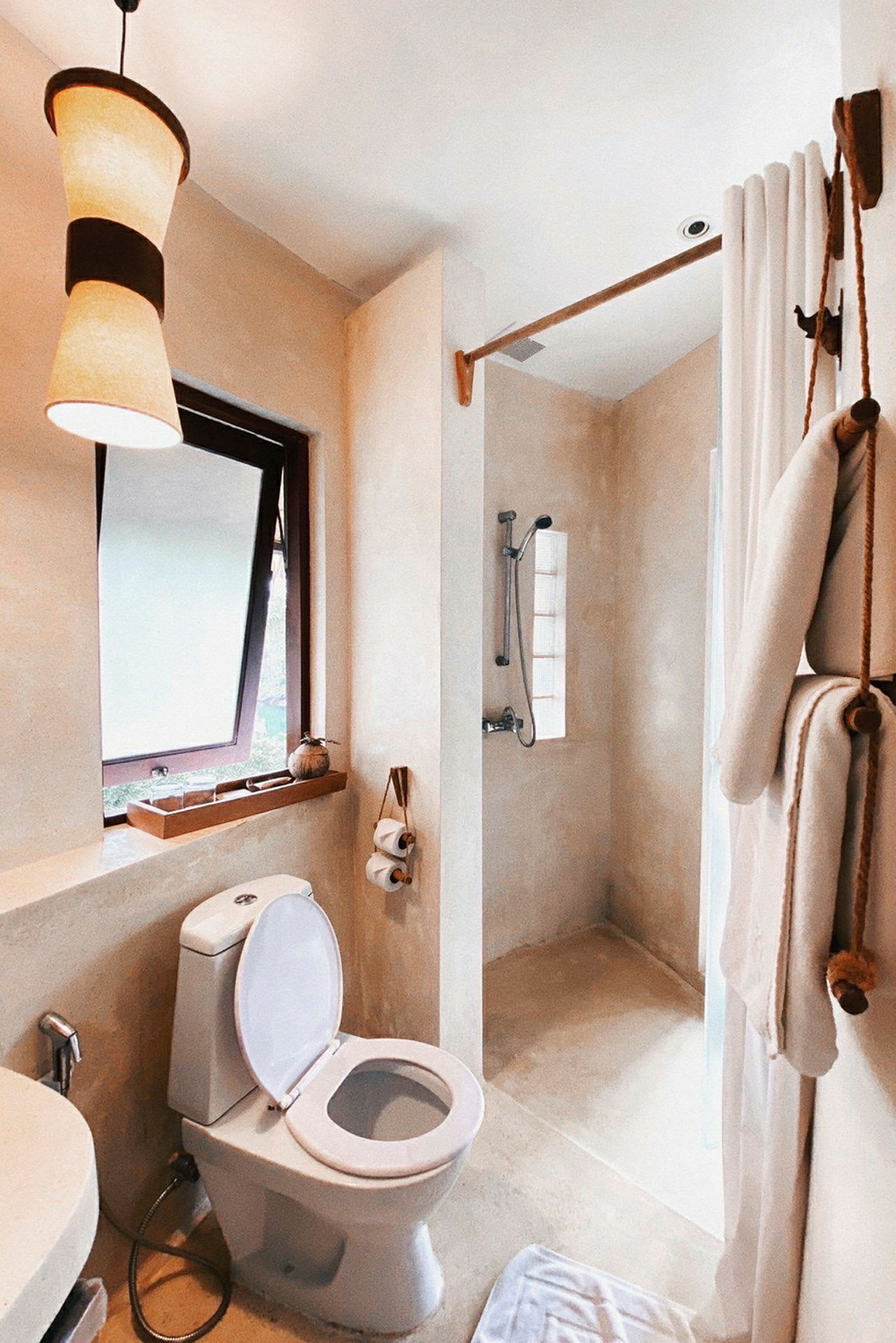 Et lyst badeværelse med toilet, bruser og vindue. (AI-genereret tekst)