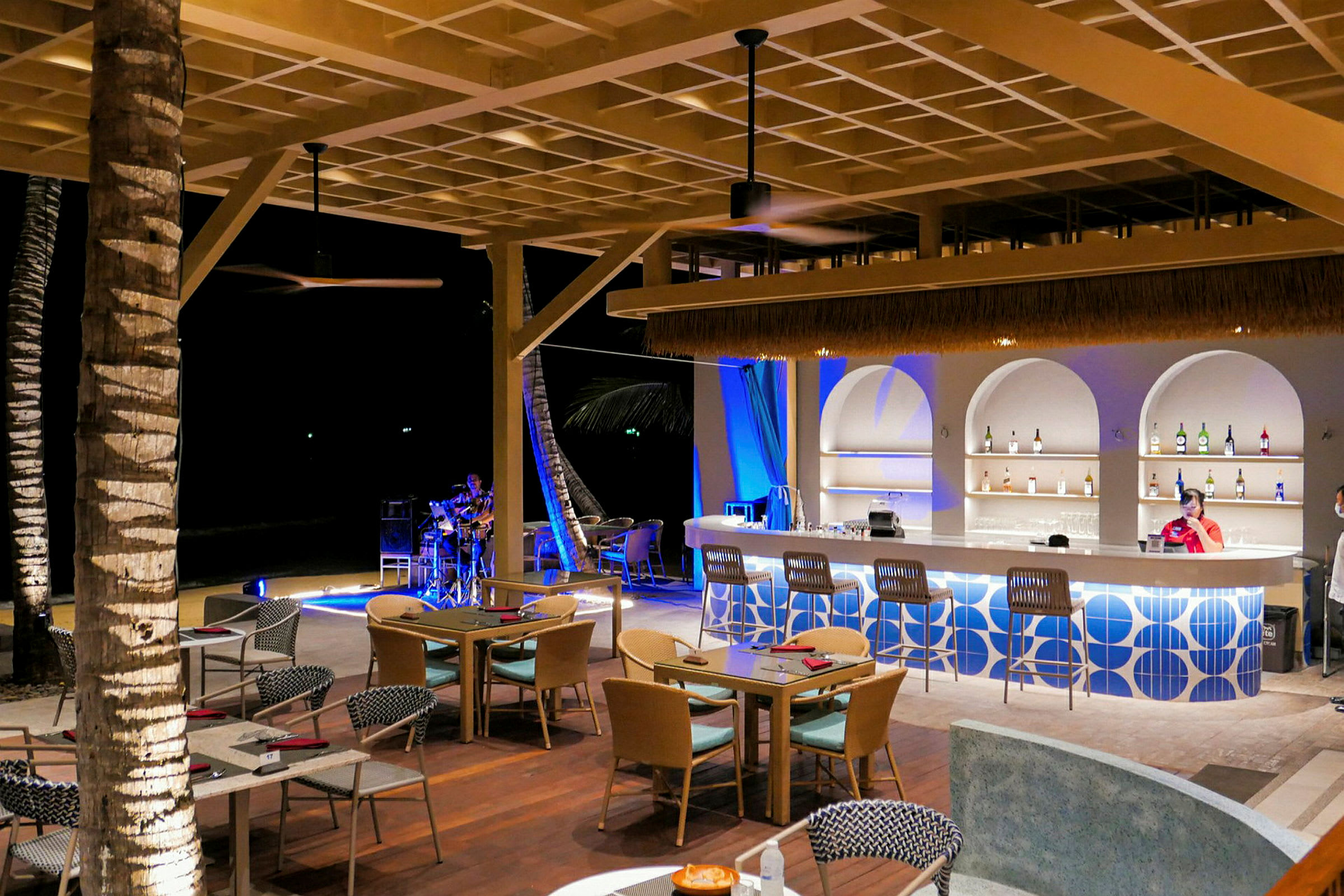 En udendørs bar og restaurant med moderne møbler og en person, der spiller musik i baggrunden. (AI-genereret tekst)