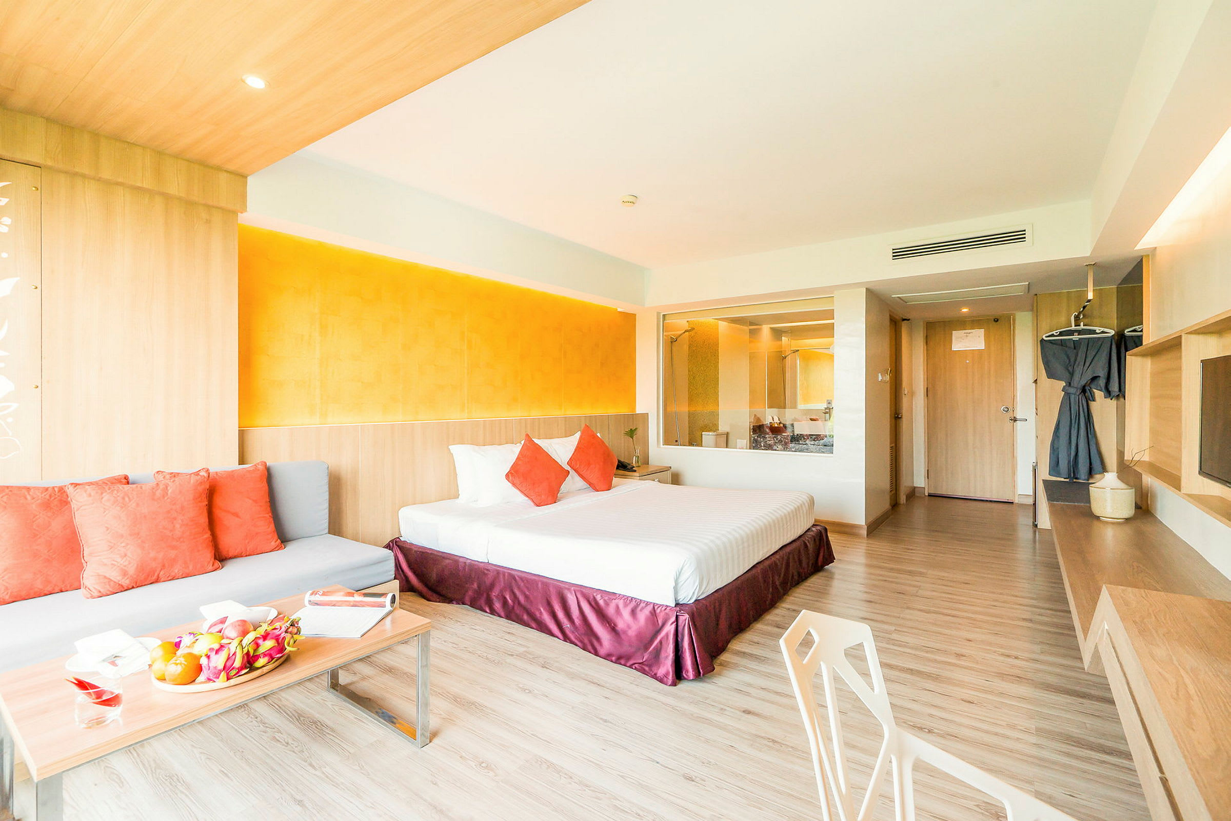 Et moderne hotelværelse med dobbeltseng, sofa med puder og et bord med frugt. (AI-genereret tekst)