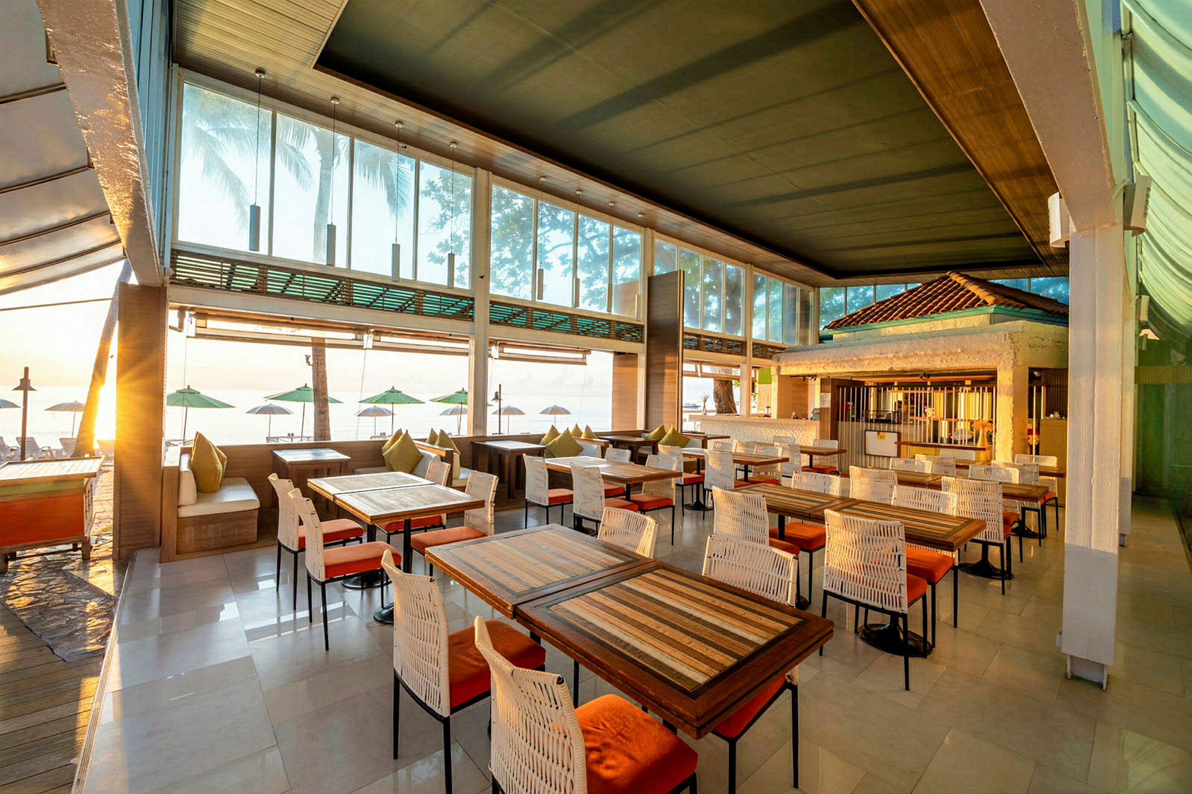 Restaurant med træborde og stole, med udsigt over stranden og havet. (AI-genereret tekst)
