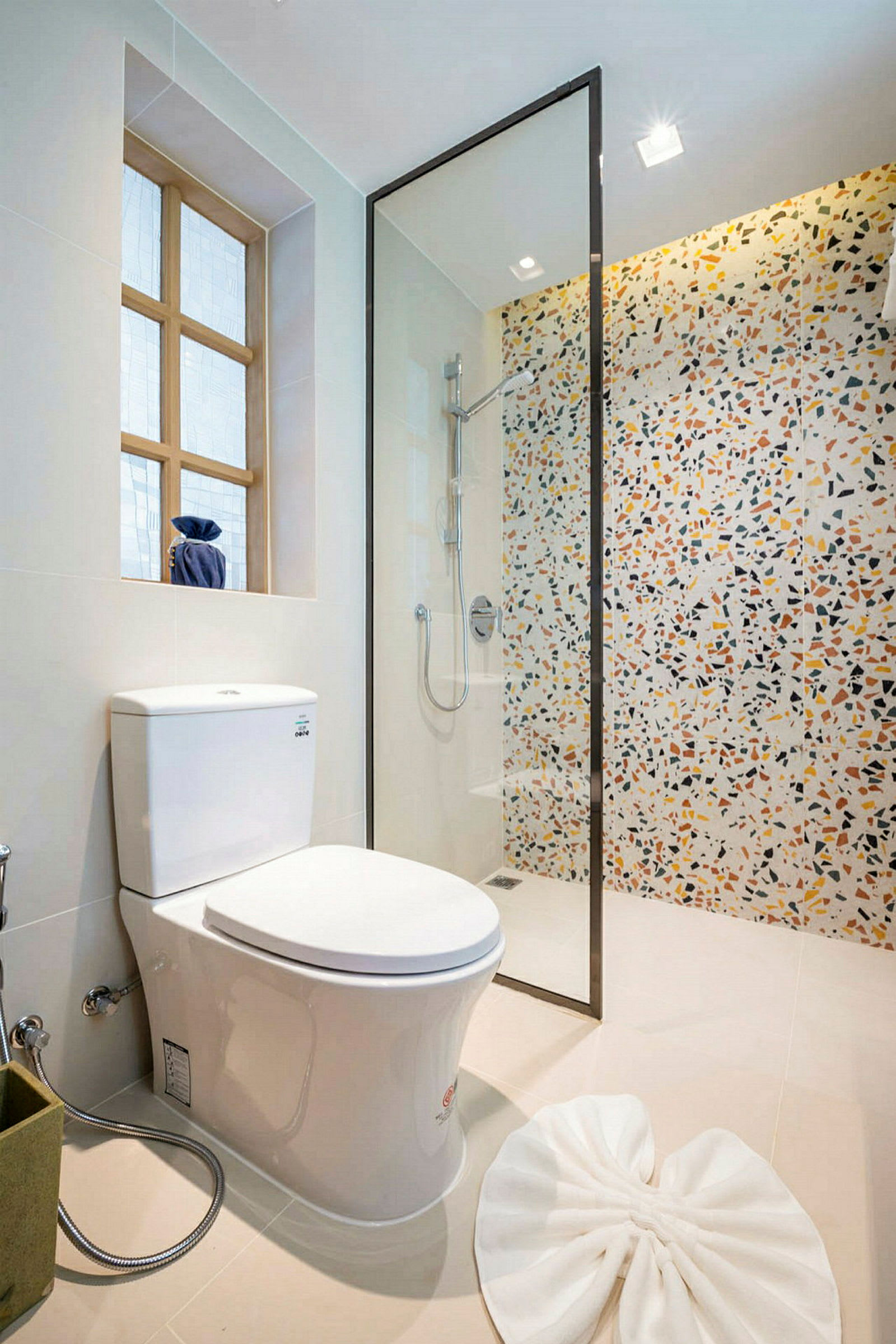 Badeværelse med toilet, brusekabine og farverig flisevæg. (AI-genereret tekst)