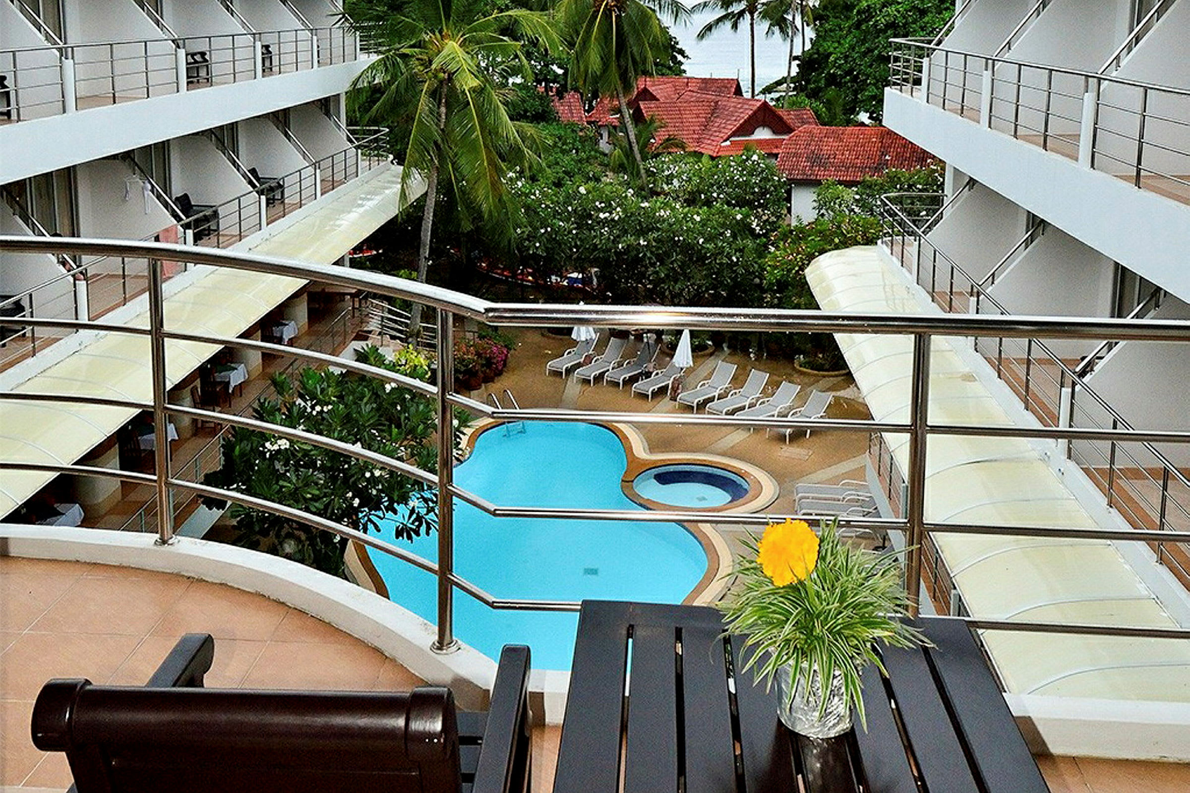 Billede af en hotelpool omgivet af liggestole, set fra en balkon med udsigt over området. (AI-genereret tekst)