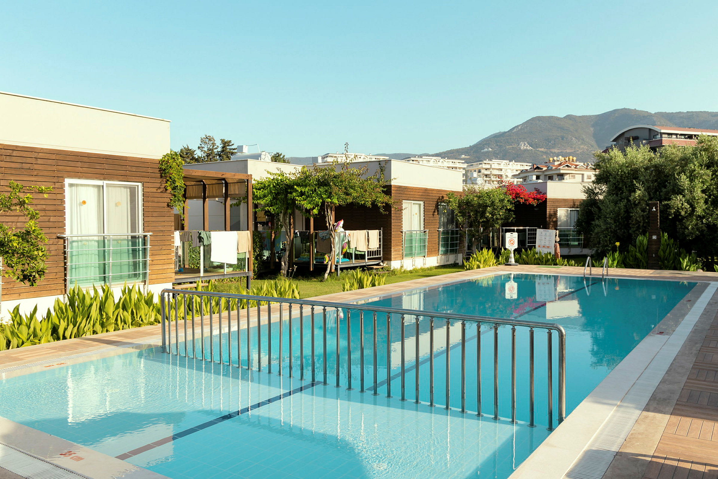 En udendørs swimmingpool omgivet af moderne bygninger og grønne områder. (AI-genereret tekst)