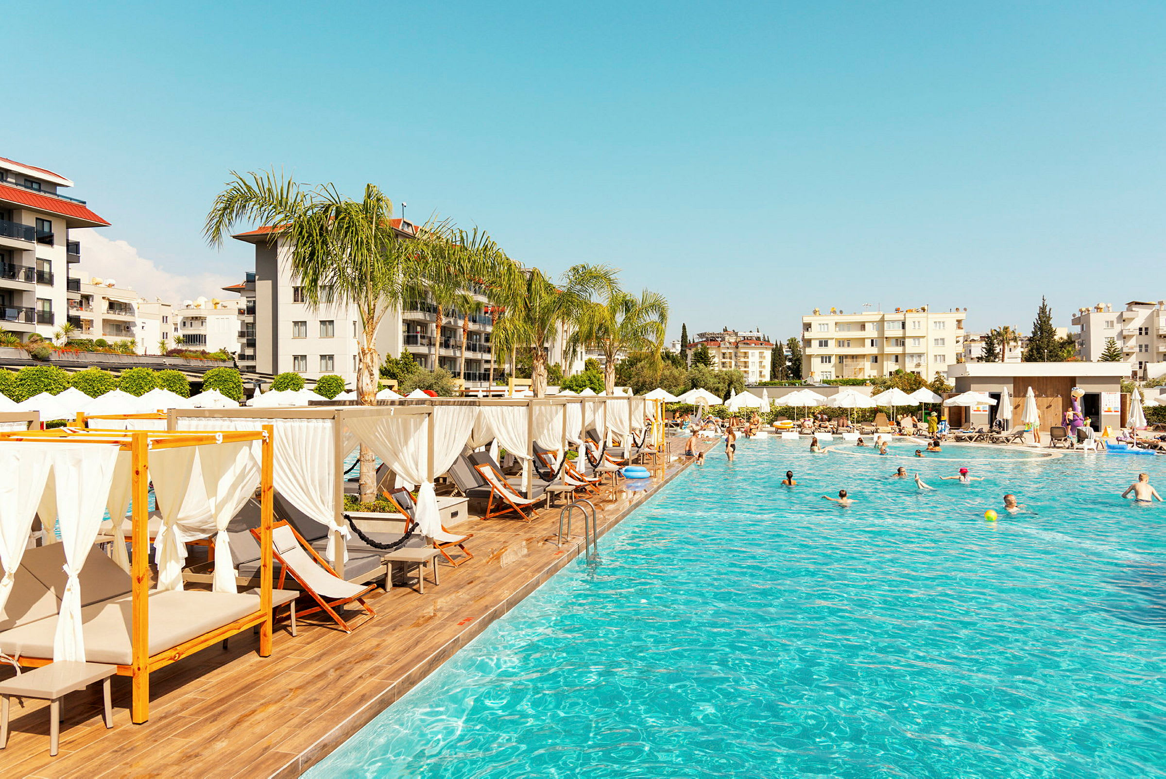 Udendørs pool med liggestole og parasoller ved et hotel. (AI-genereret tekst)