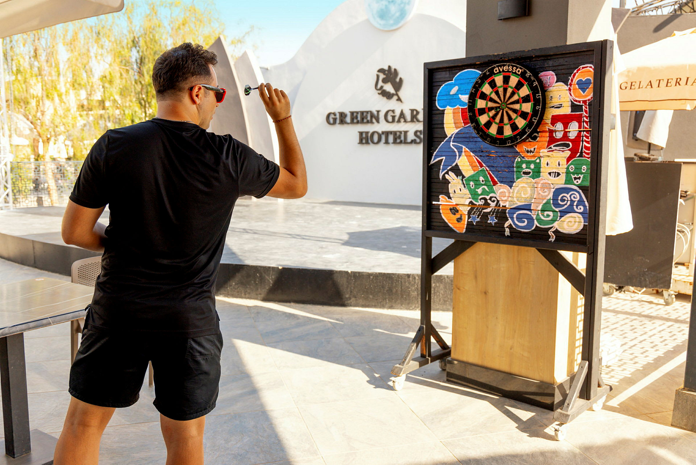 Mand spiller dart foran en farverig darttavle på hotellet. (AI-genereret tekst)