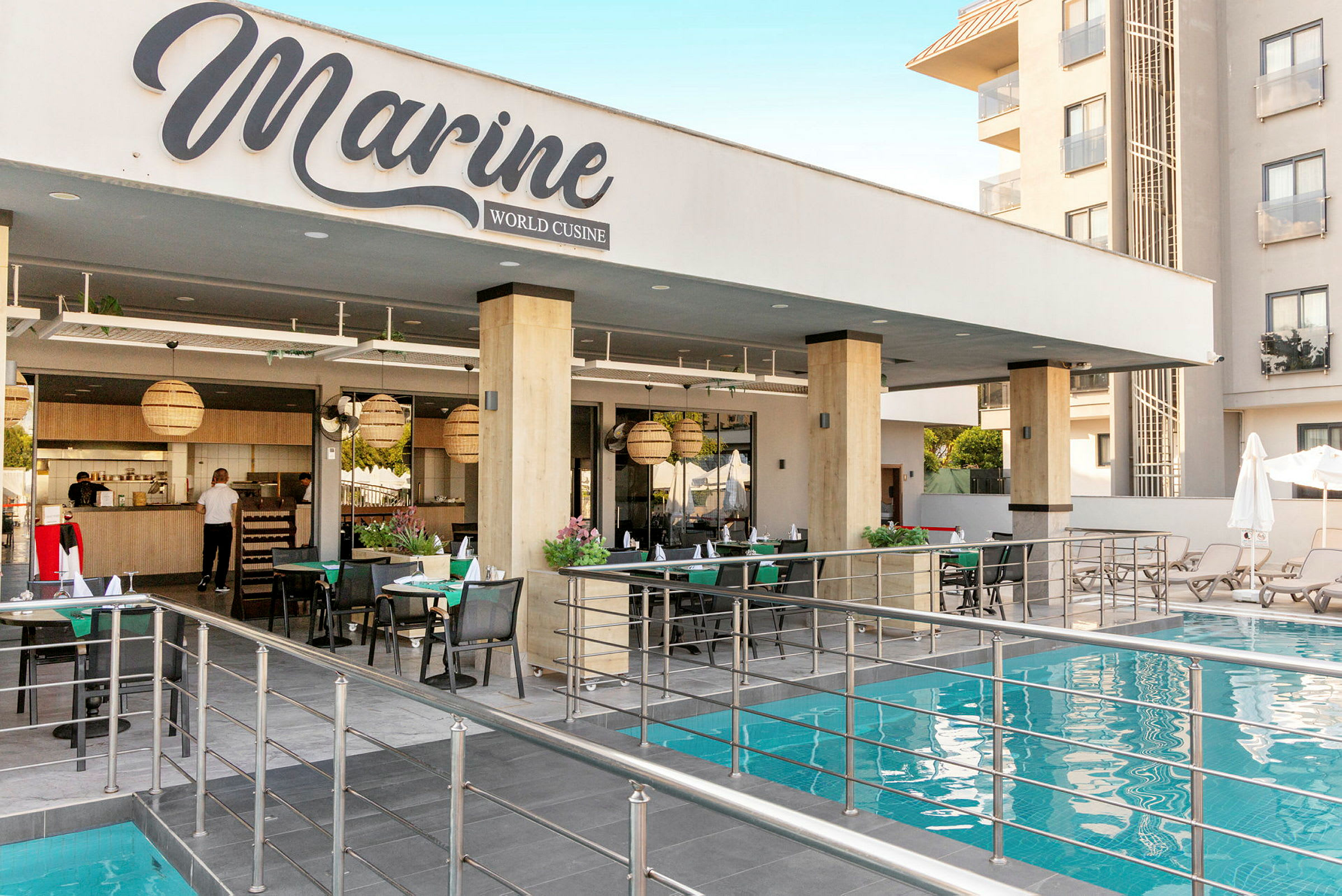 En restaurant ved navn Marine World Cuisine beliggende ved siden af en pool med siddepladser og borde. (AI-genereret tekst)