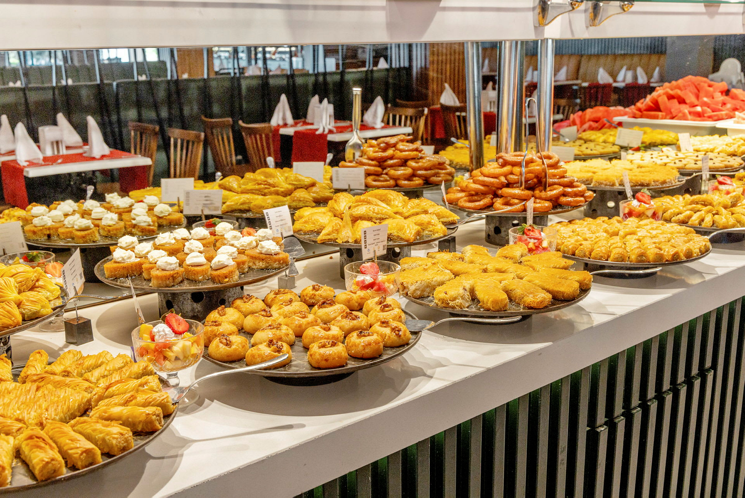 En buffet med et bredt udvalg af bagværk og søde sager anrettet på en hvid bænk. (AI-genereret tekst)