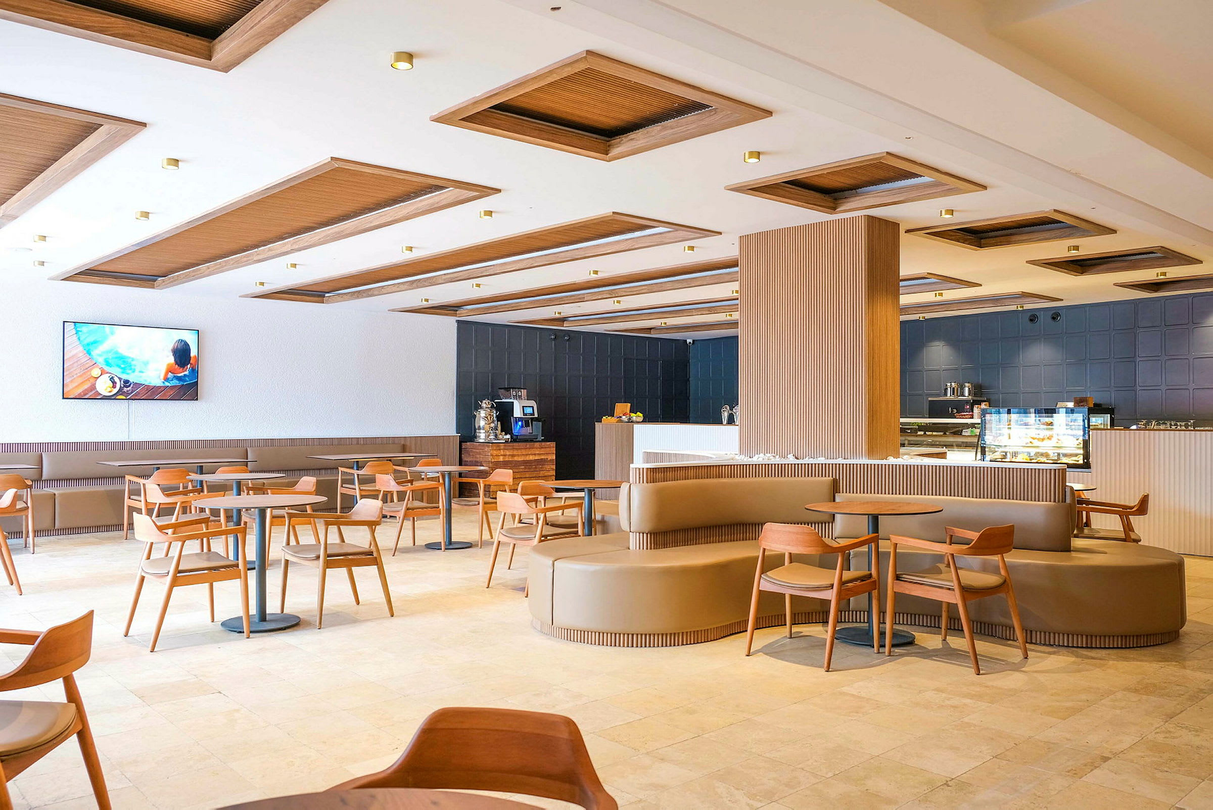 En moderne restaurant med træelementer, borde og stole samt en bar og en TV på væggen. (AI-genereret tekst)
