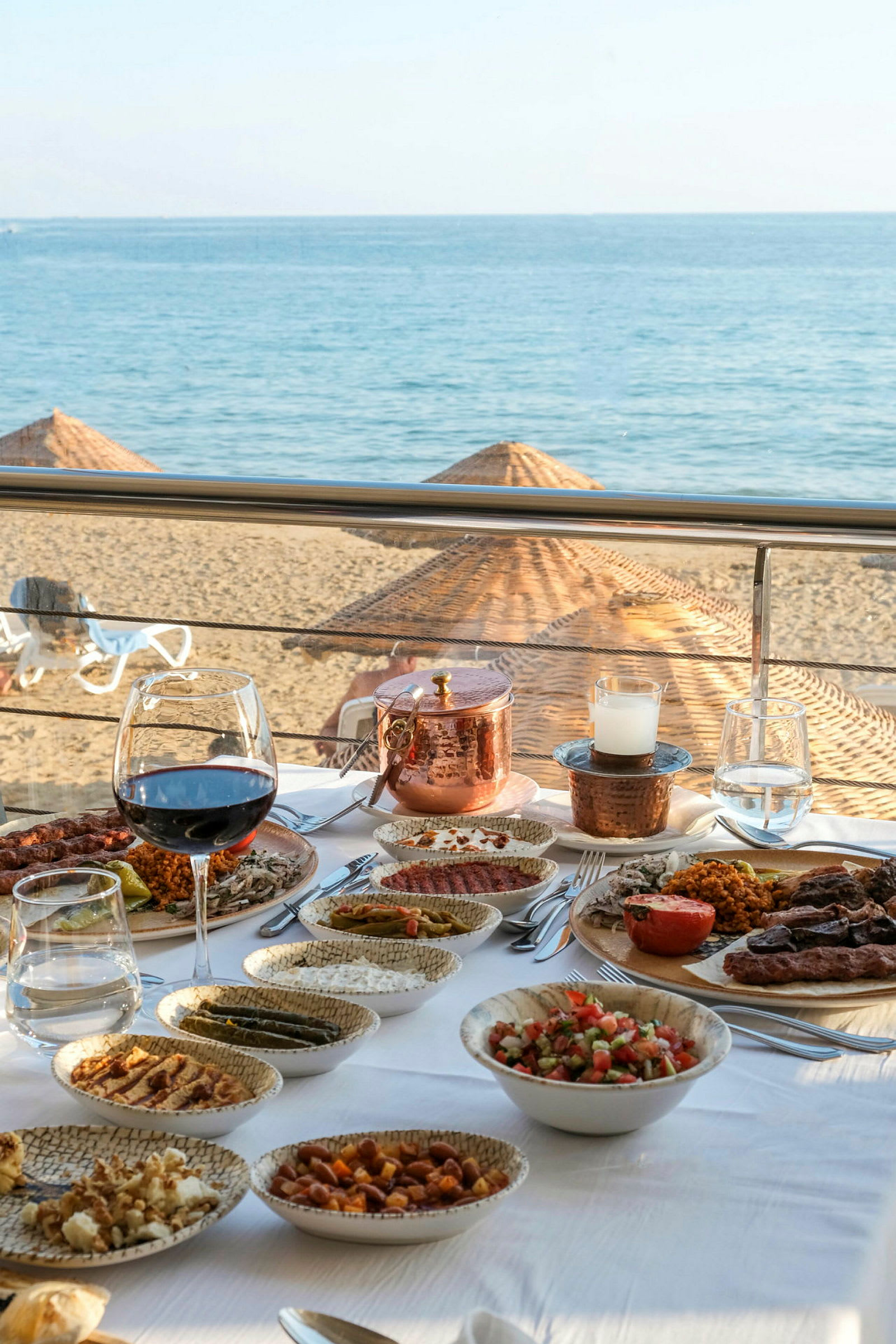 Et bord på en strandrestaurant med forskellige retter og drinks, med udsigt over havet. (AI-genereret tekst)