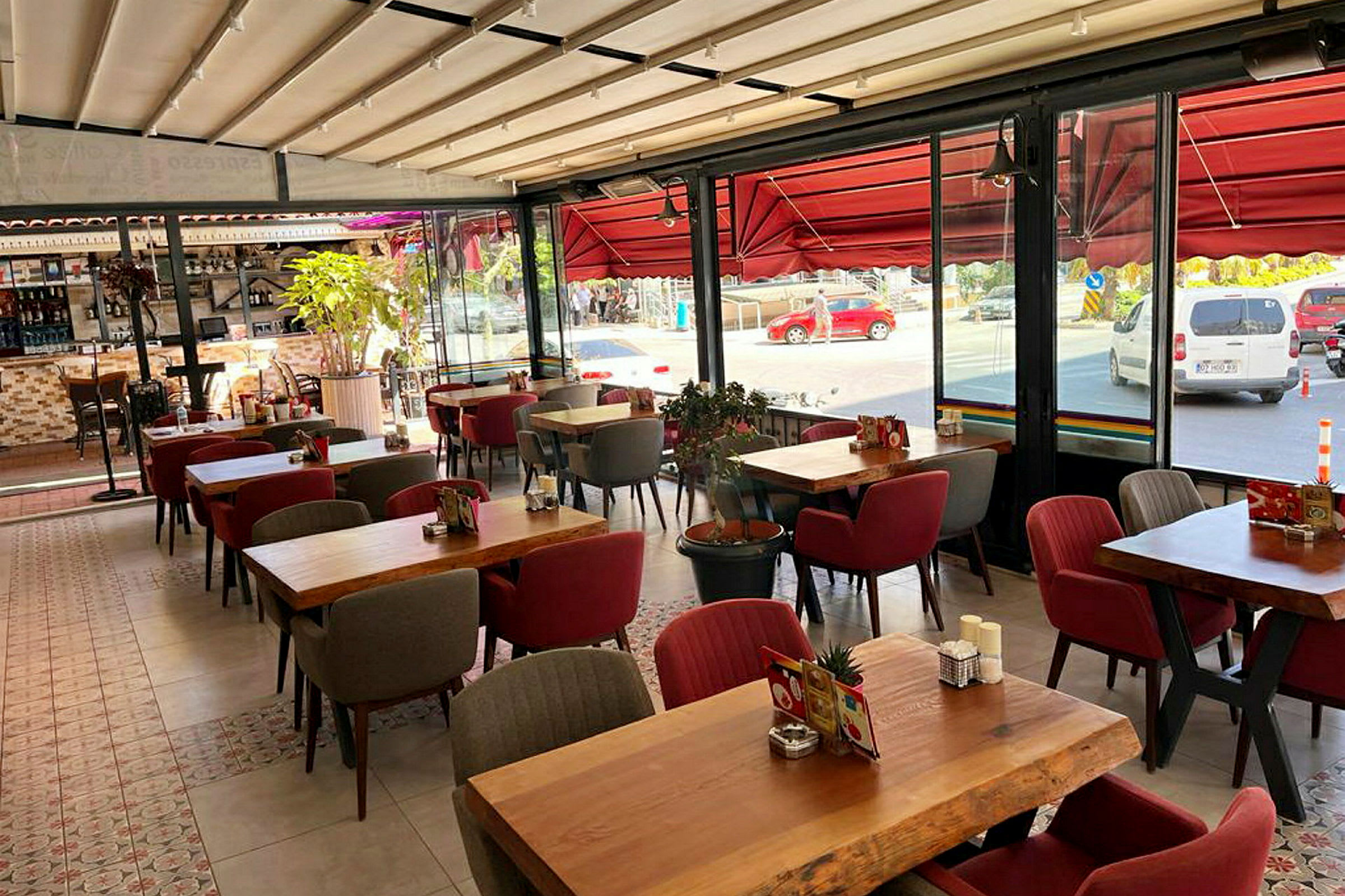 En restaurant med borde og stole samt store vinduer ud mod gaden. (AI-genereret tekst)
