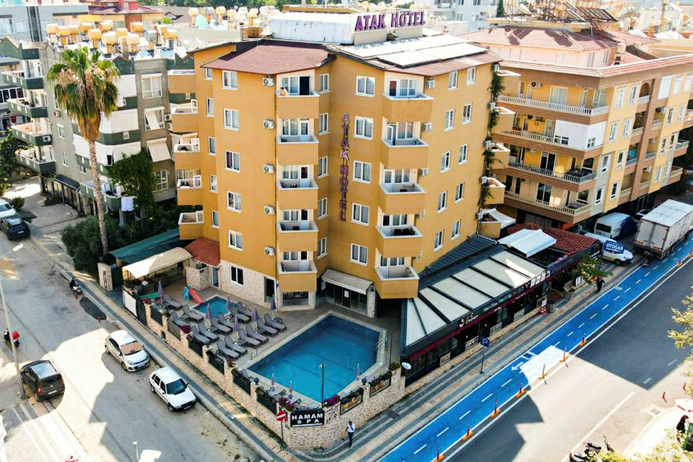 Et hotel ved en vej med en udendørs pool, liggestole og en lille siddegruppe. (AI-genereret tekst)