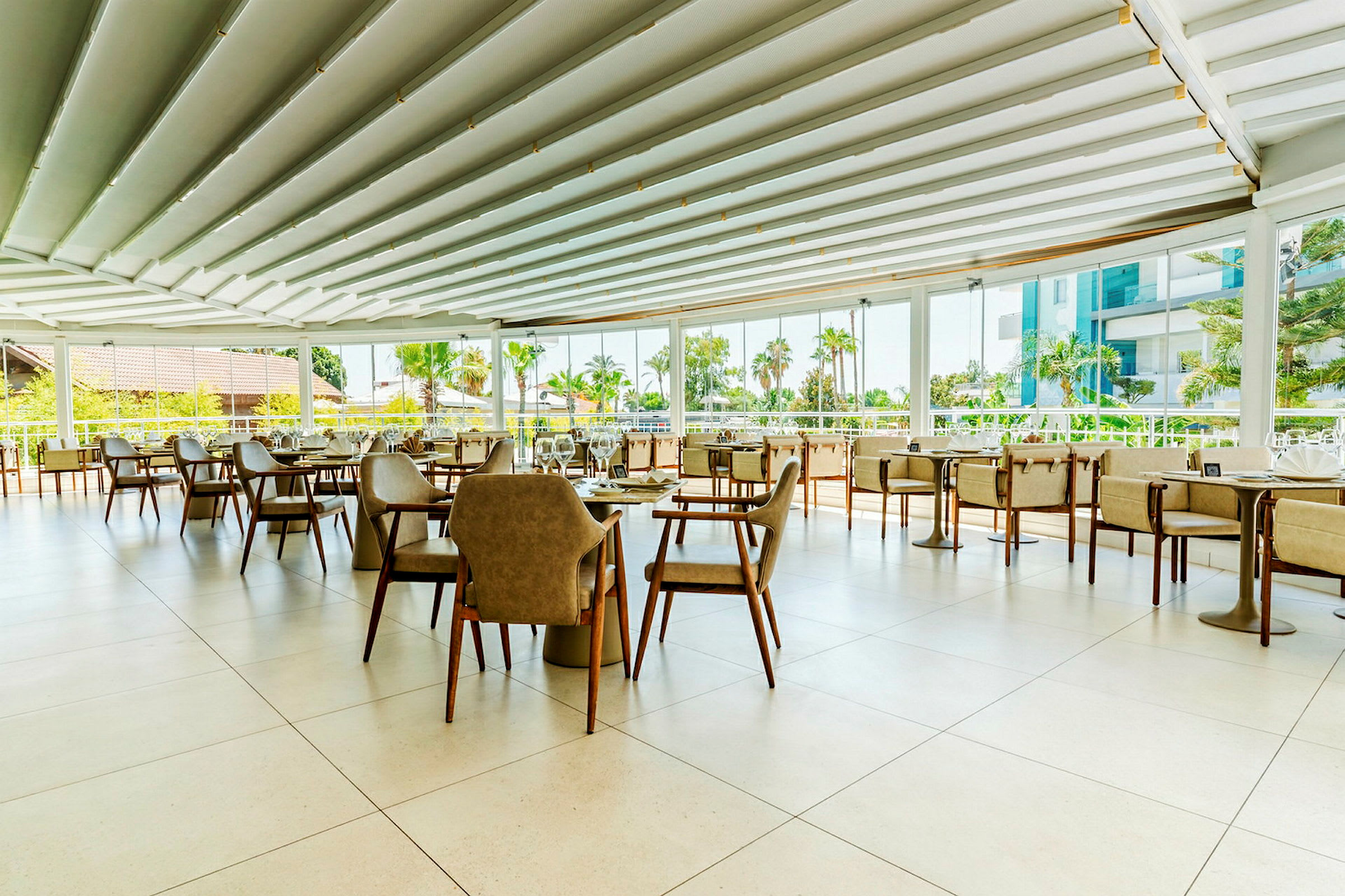 Lyse og moderne møbler i en restaurant med åbent loft og panoramavinduer med udsigt til en frodig udsigt. (AI-genereret tekst)