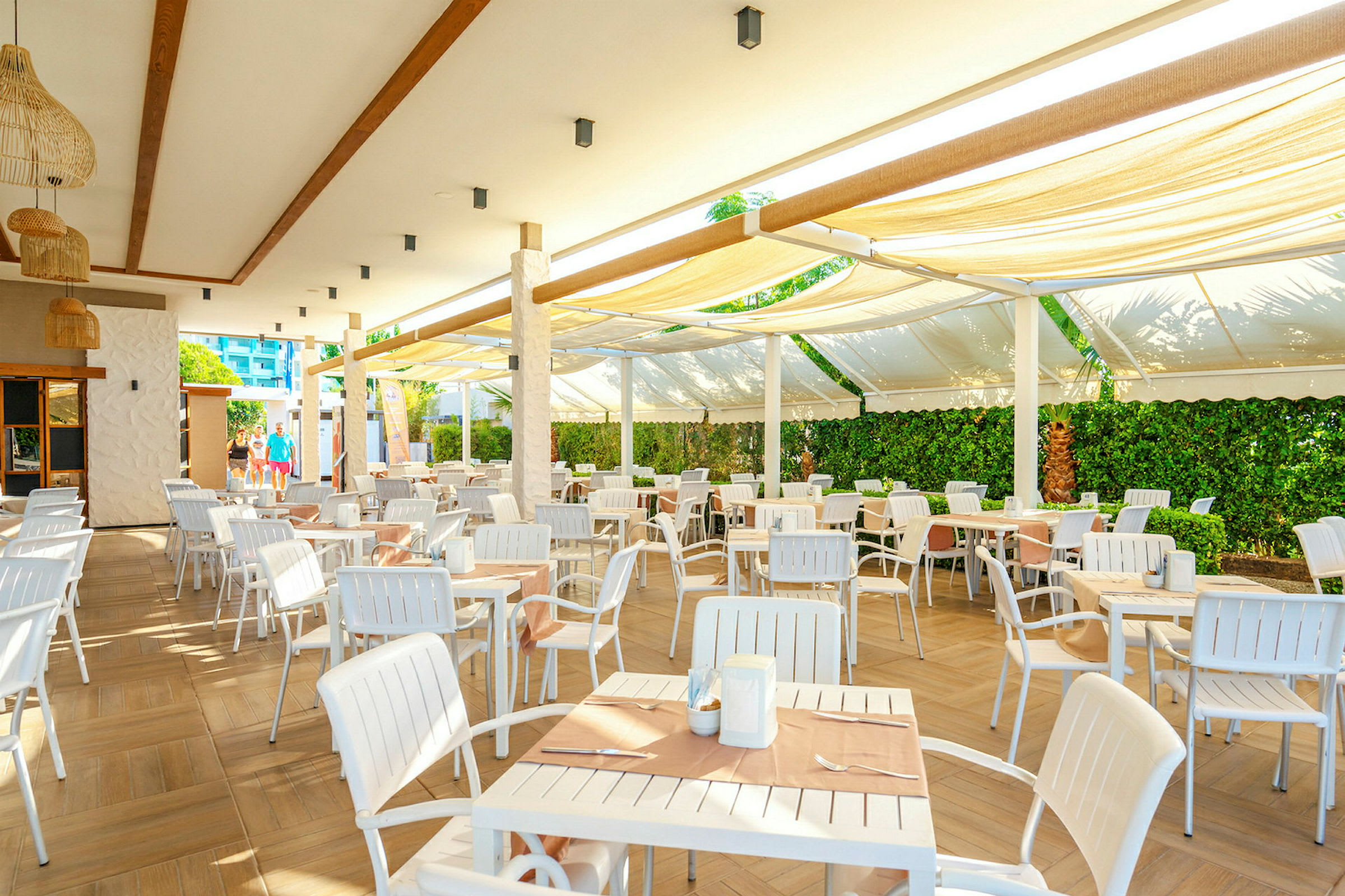 Udendørs serveringsområde med hvide borde og stole under en overdækket terrasse. (AI-genereret tekst)