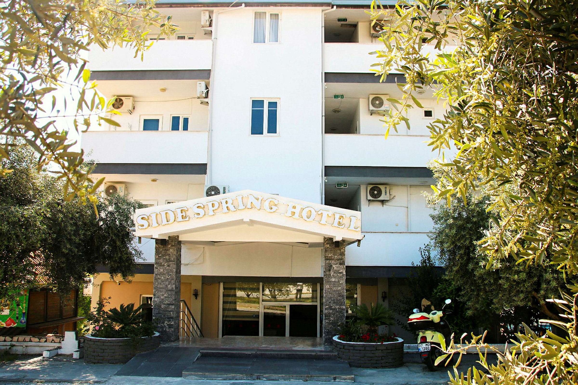 Billede af en hotelbygning med et skilt, hvor der står 'Side Spring Hotel'. (AI-genereret tekst)