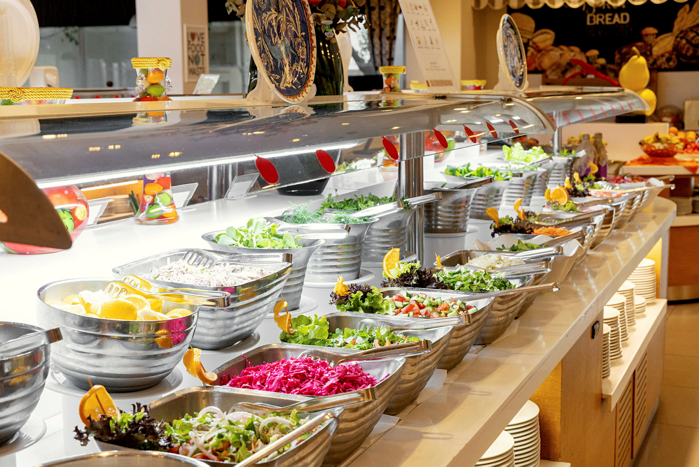 En buffet med forskellige salater og tilbehør i skåle på et bord. (AI-genereret tekst)