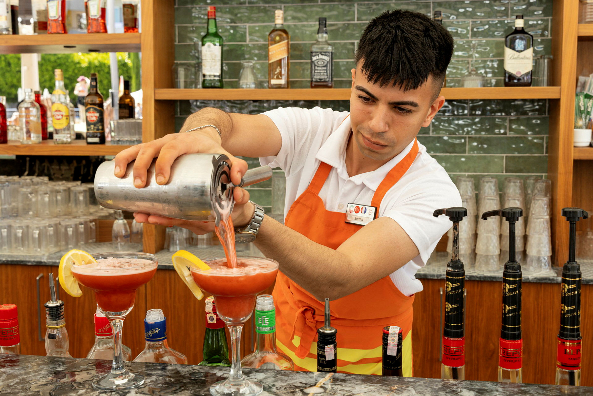 En bartender hælder en rød drik i cocktailglas. (AI-genereret tekst)