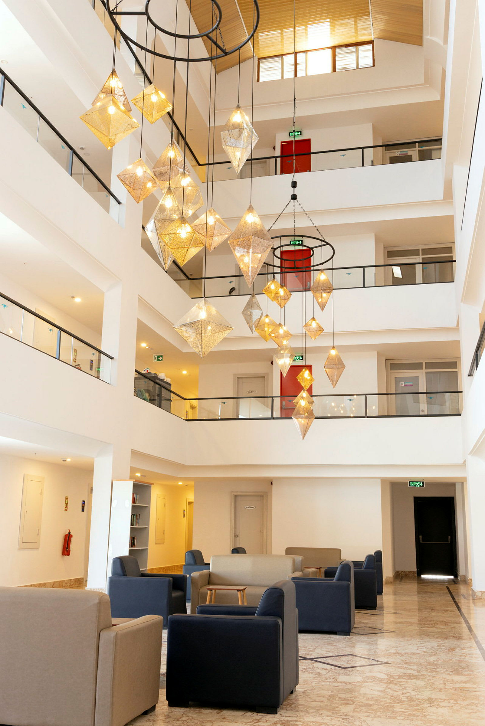 Interiør af et hotel med siddepladser og en stor lysekrone. (AI-genereret tekst)