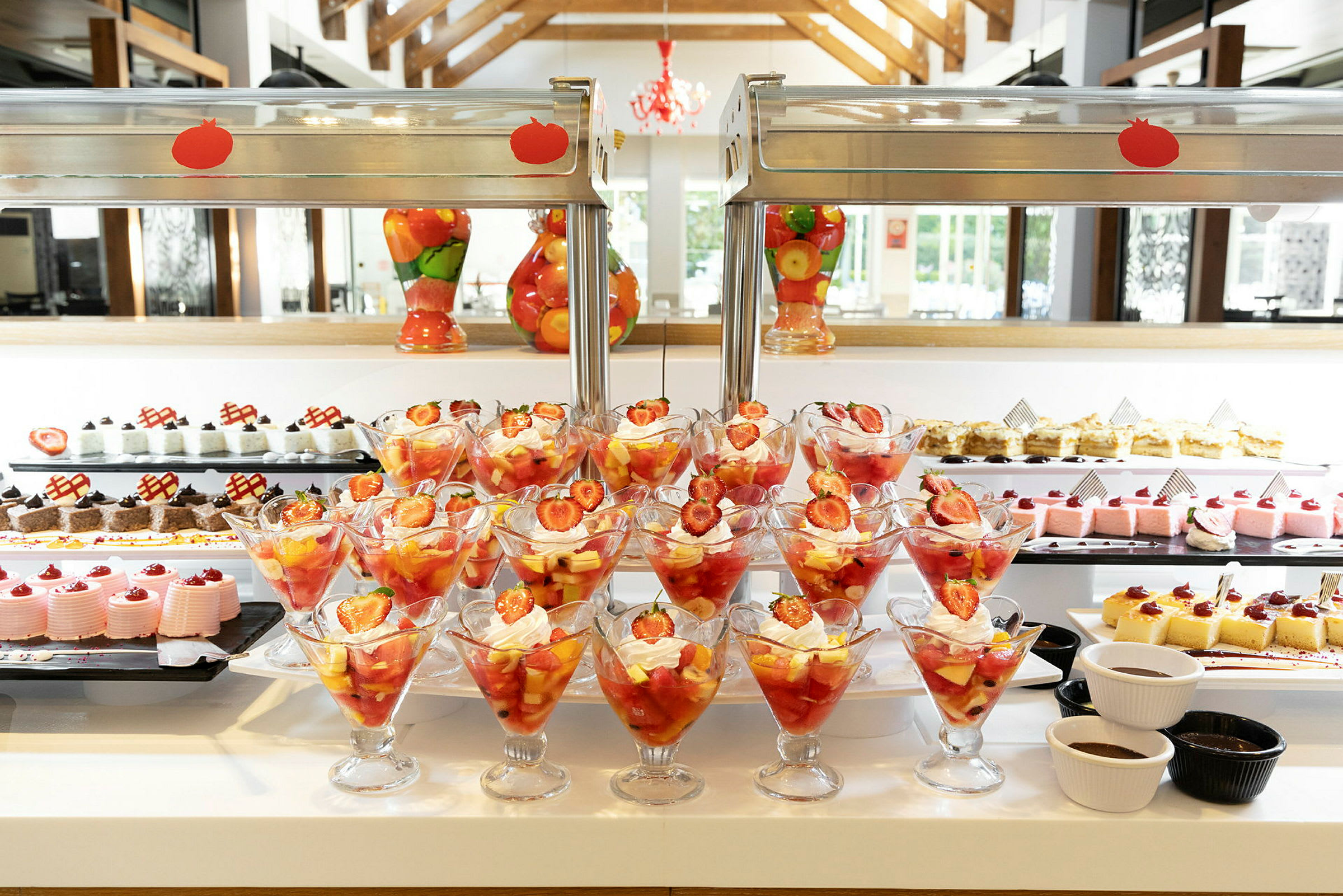 Frugtcocktail med jordbær og flødeskum i glas foran et dessertbord. (AI-genereret tekst)