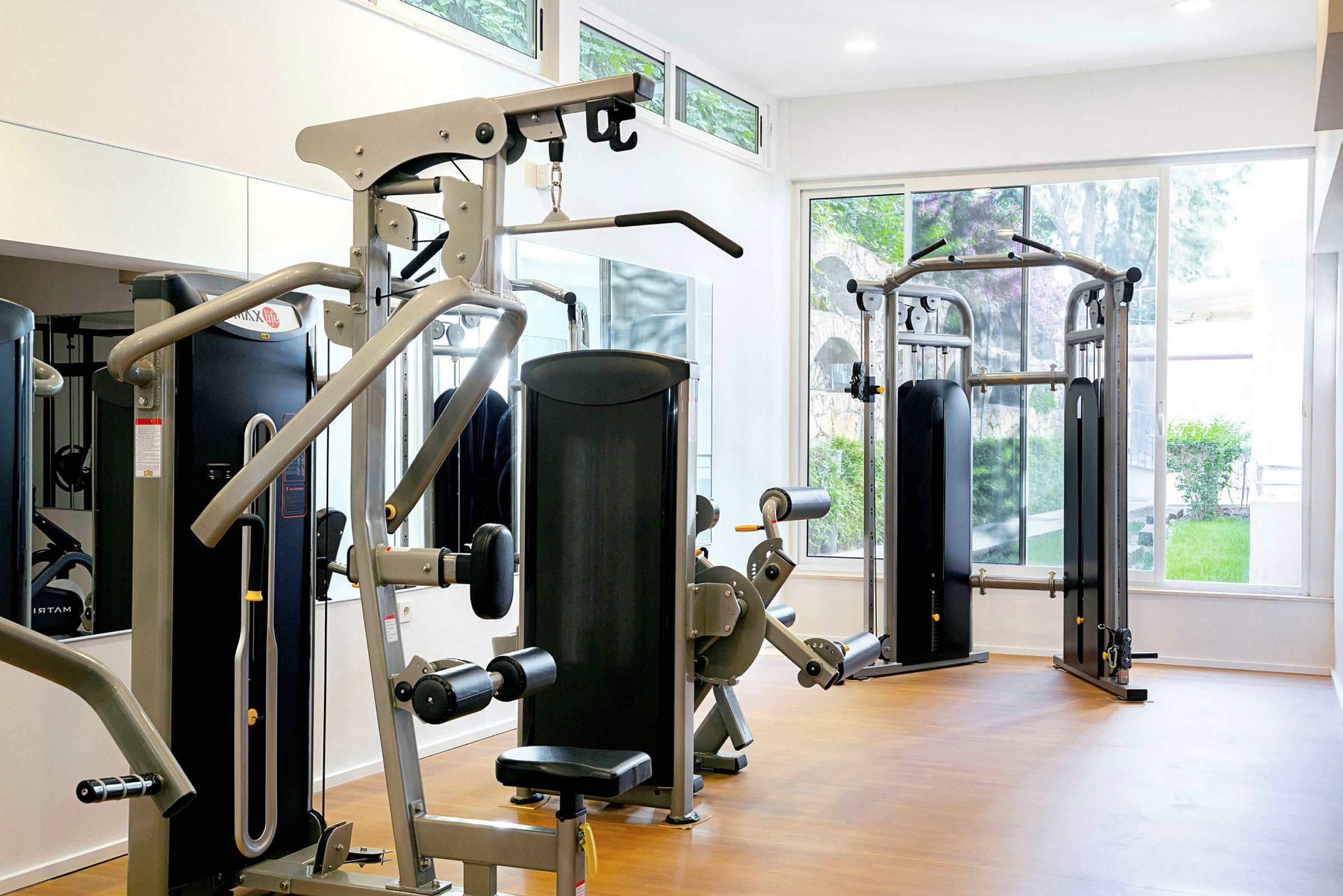 Et fitnessrum med træningsmaskiner og store vinduer. (AI-genereret tekst)