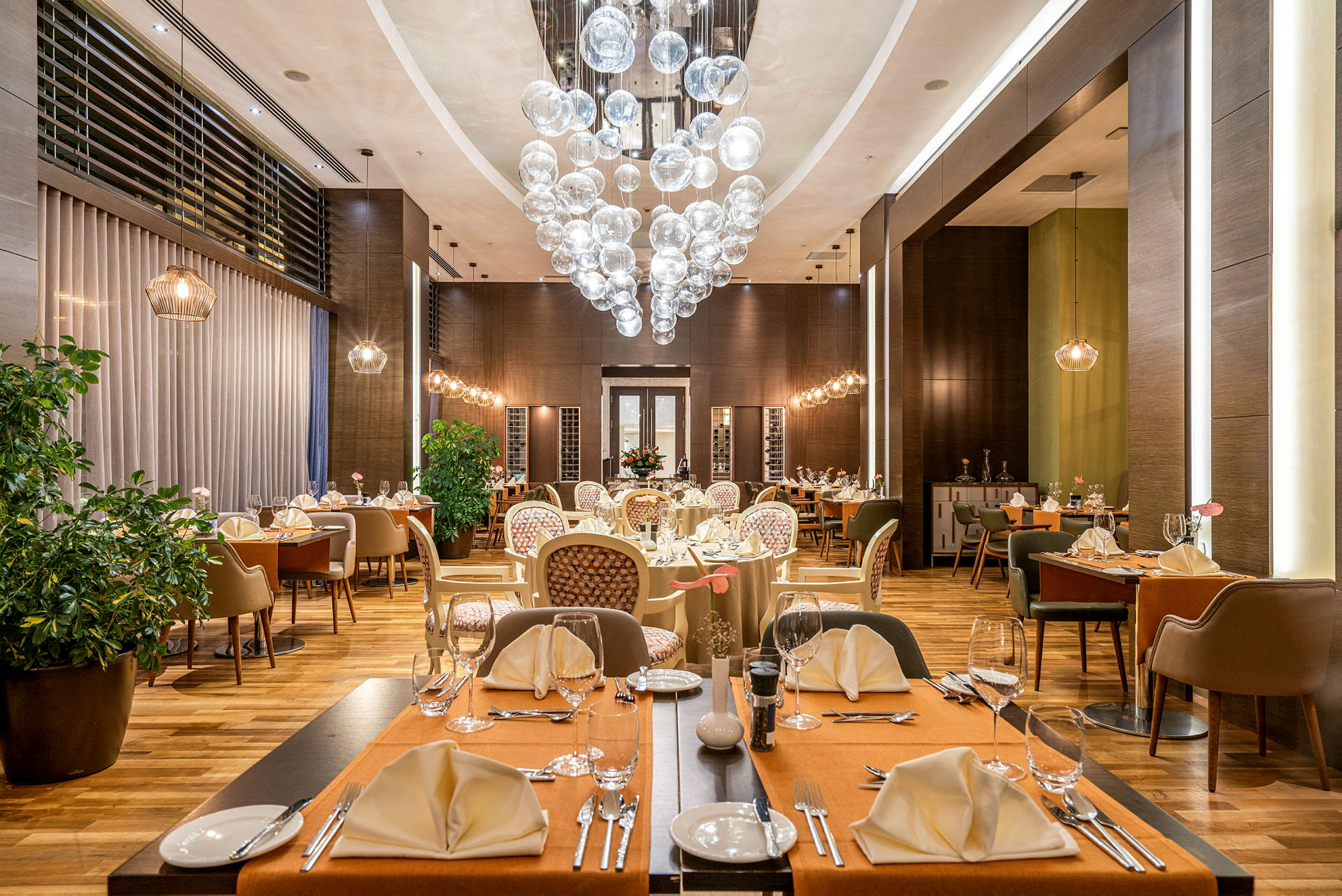 En elegant restaurant med dækkede borde, stole og en dekorativ lysekrone. (AI-genereret tekst)