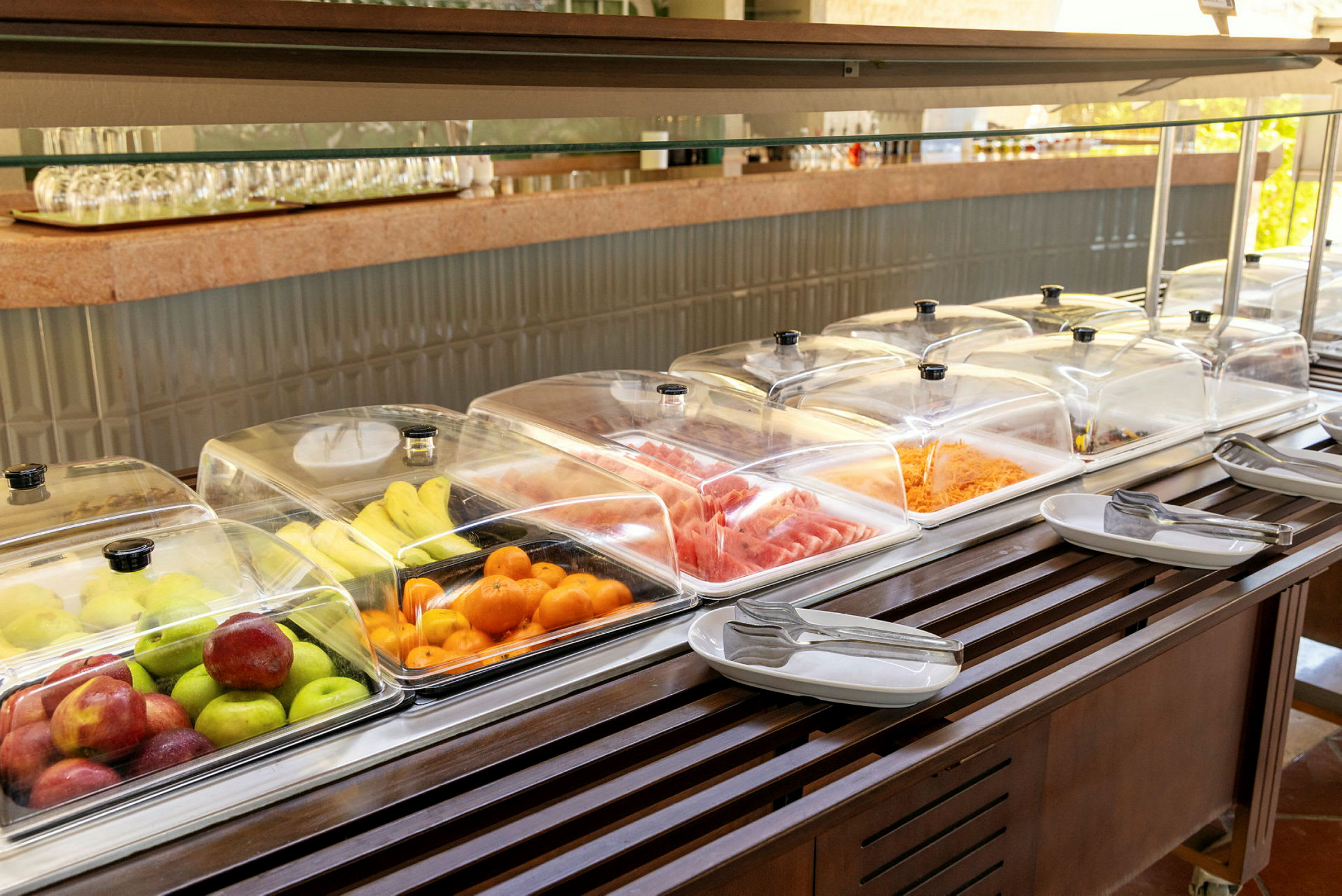 Buffetbord med frugt, grøntsager og kolde retter under gennemsigtige låg. (AI-genereret tekst)