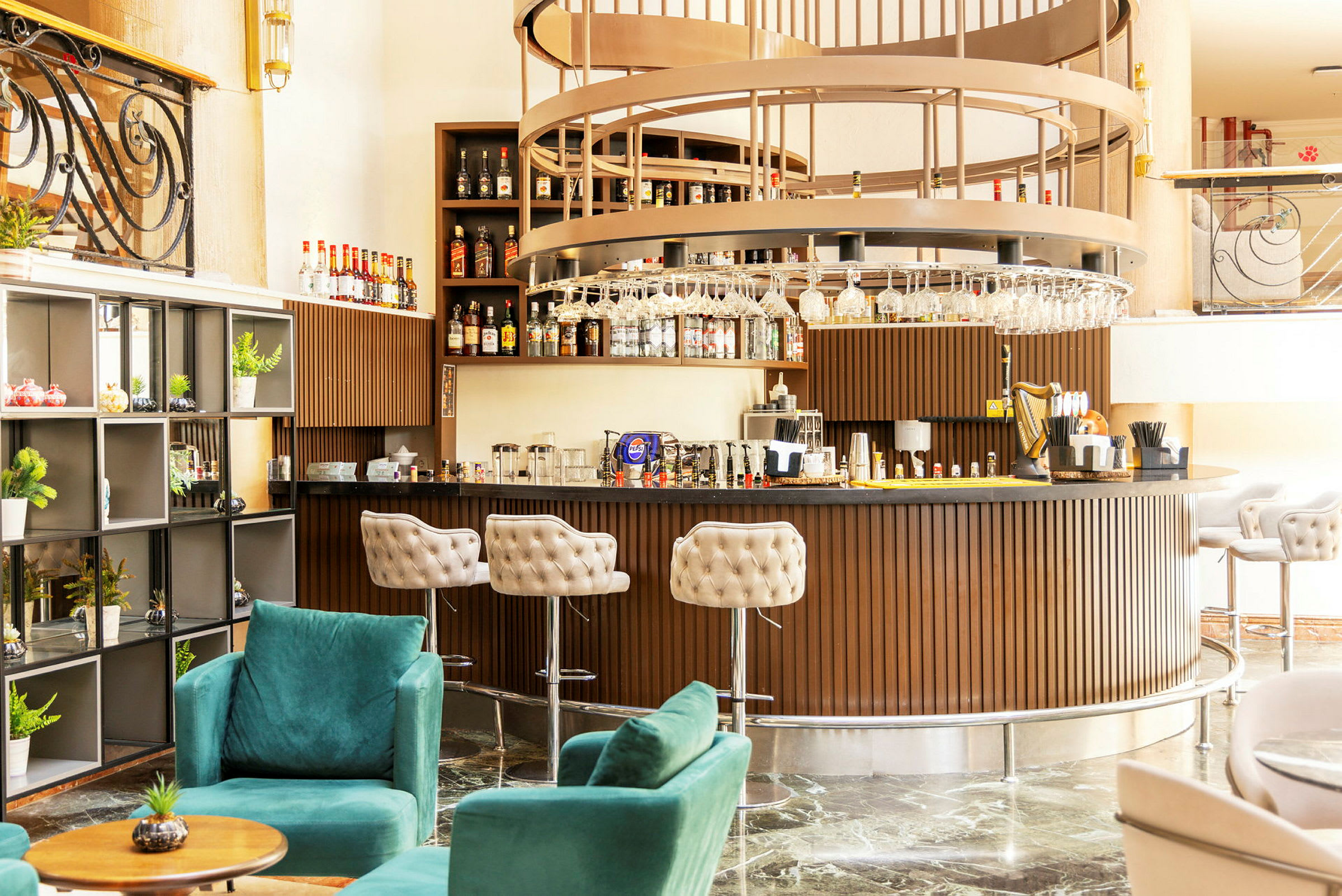 En stilfuld hotelbar med elegant indretning, inklusive grønne lænestole og en rund bardisk i trædesign. (AI-genereret tekst)