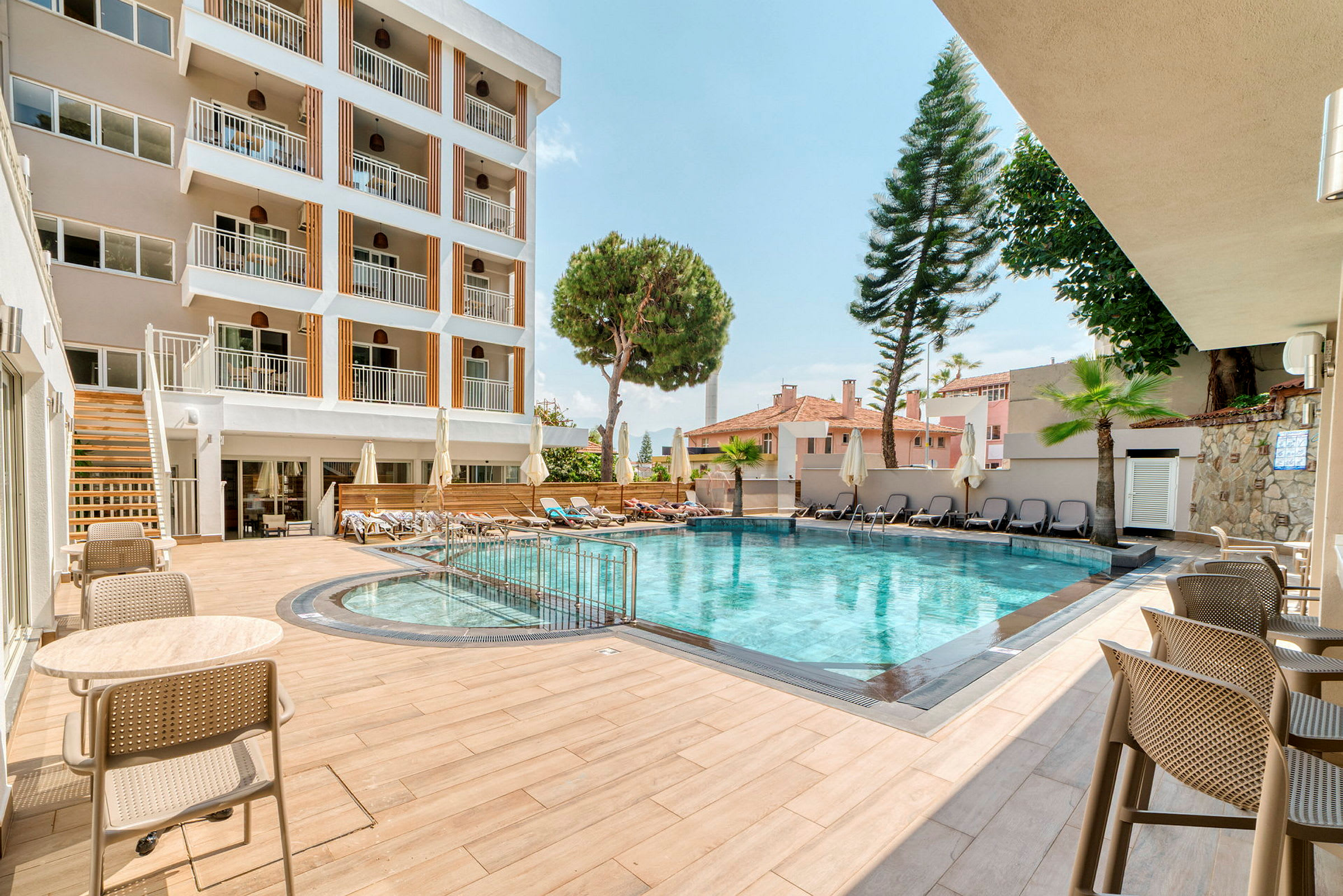Hotellets udendørs pool med siddepladser og liggestole. (AI-genereret tekst)