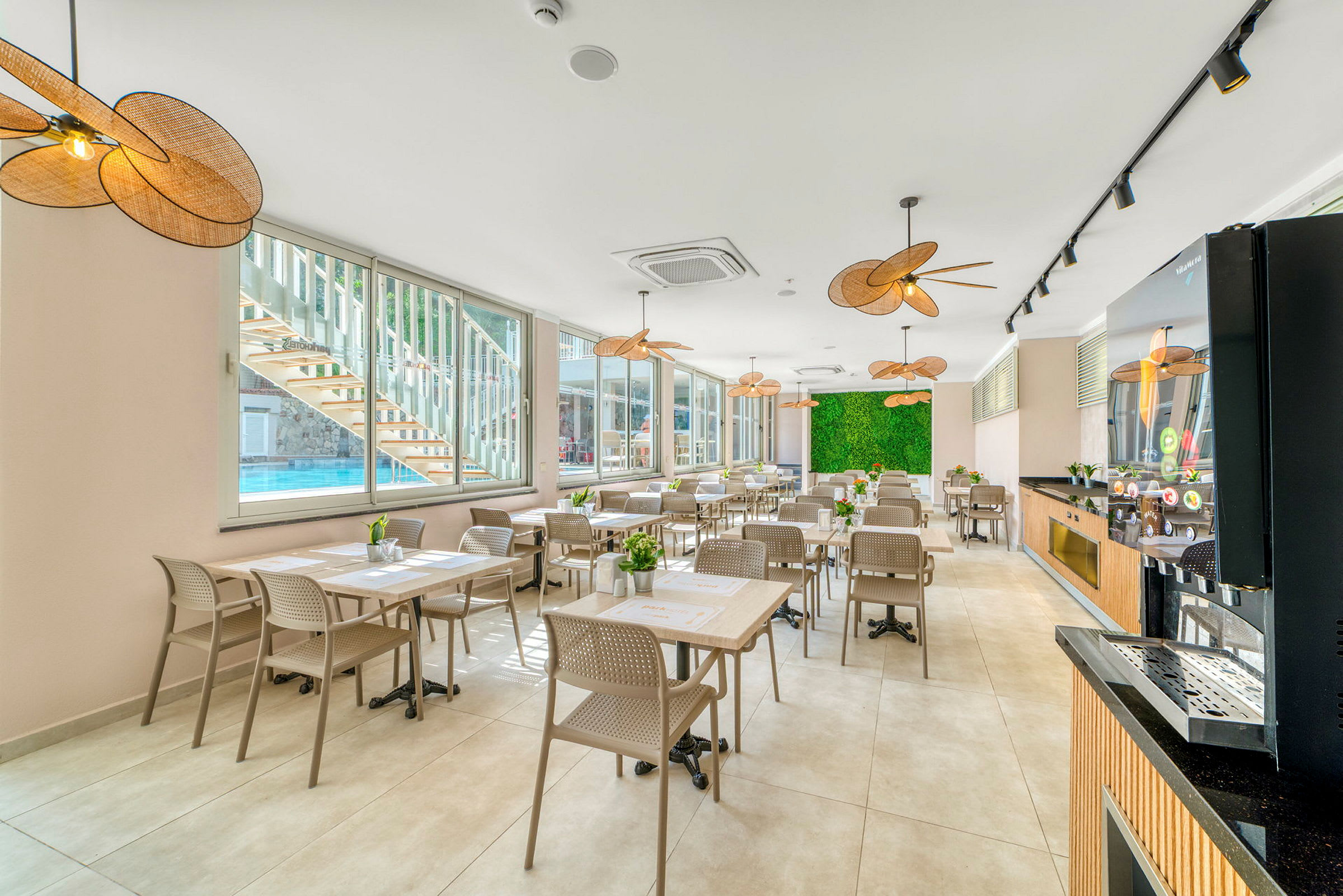 Restaurant med borde og stole, store vinduer og grøn dekorativ væg. (AI-genereret tekst)