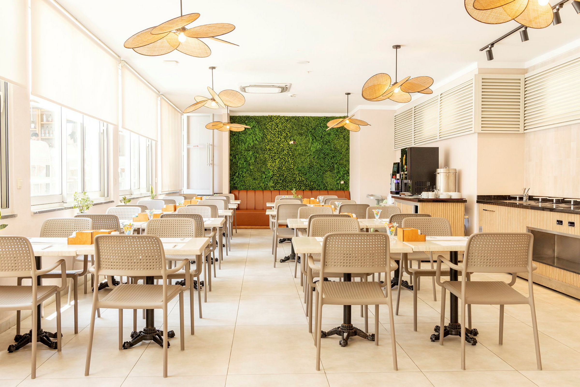 En spisestue med opstillede borde og stole. Grøn vægdekoration i baggrunden. (AI-genereret tekst)