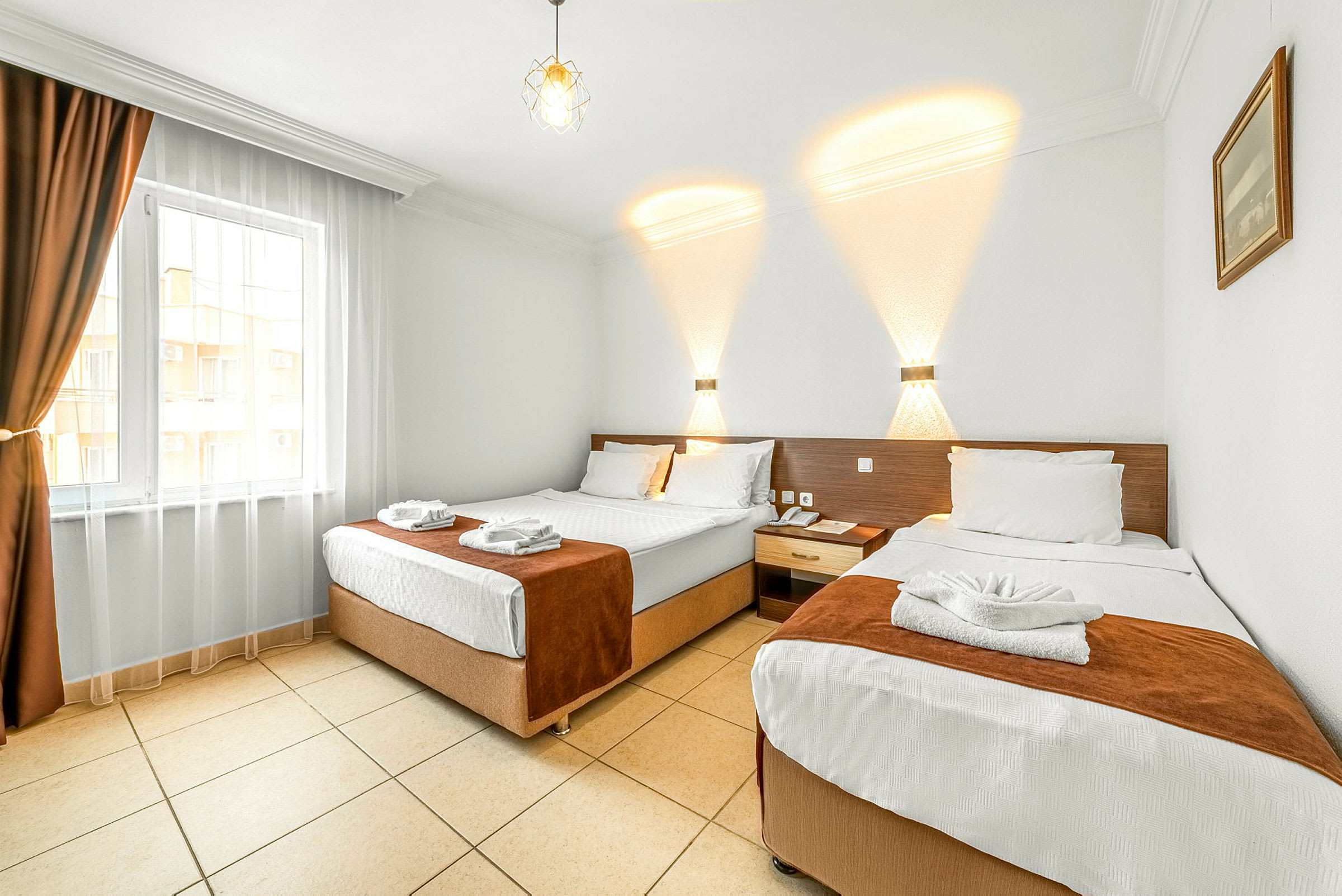 Hotelværelse med to separate senge, lys indretning og et vindue med mørke gardiner. (AI-genereret tekst)