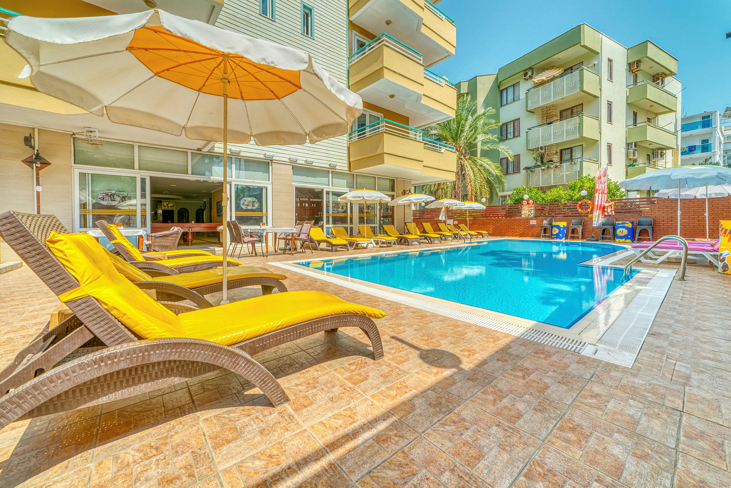 Udendørs swimmingpool med liggestole og parasoller ved et hotel. (AI-genereret tekst)