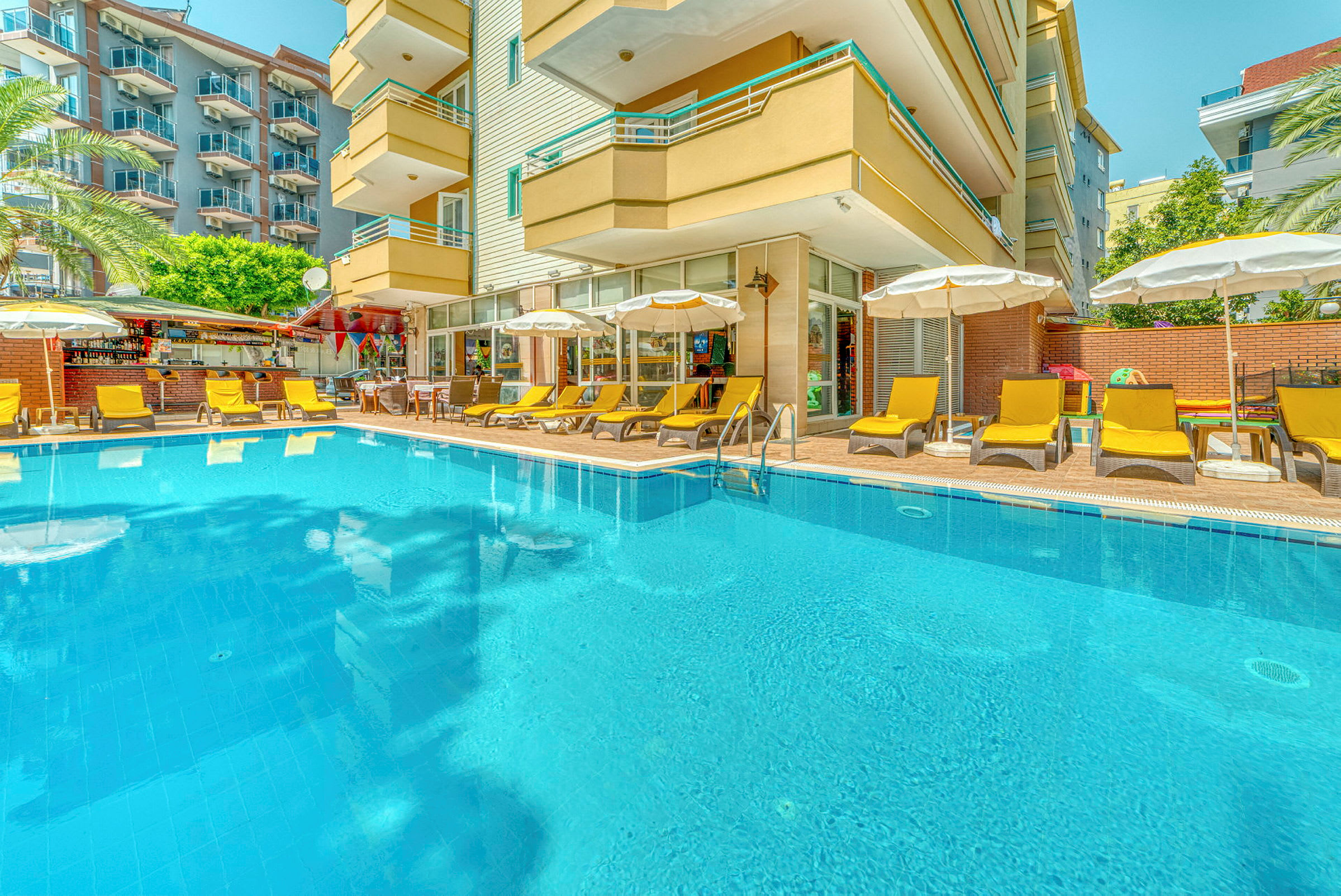 En udendørs pool omgivet af liggestole og parasoller ved et hotel. (AI-genereret tekst)