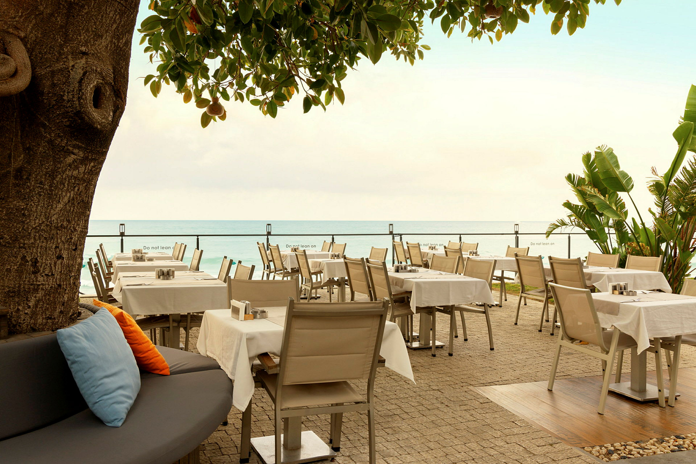 Restaurant med borde og stole ved havet. (AI-genereret tekst)
