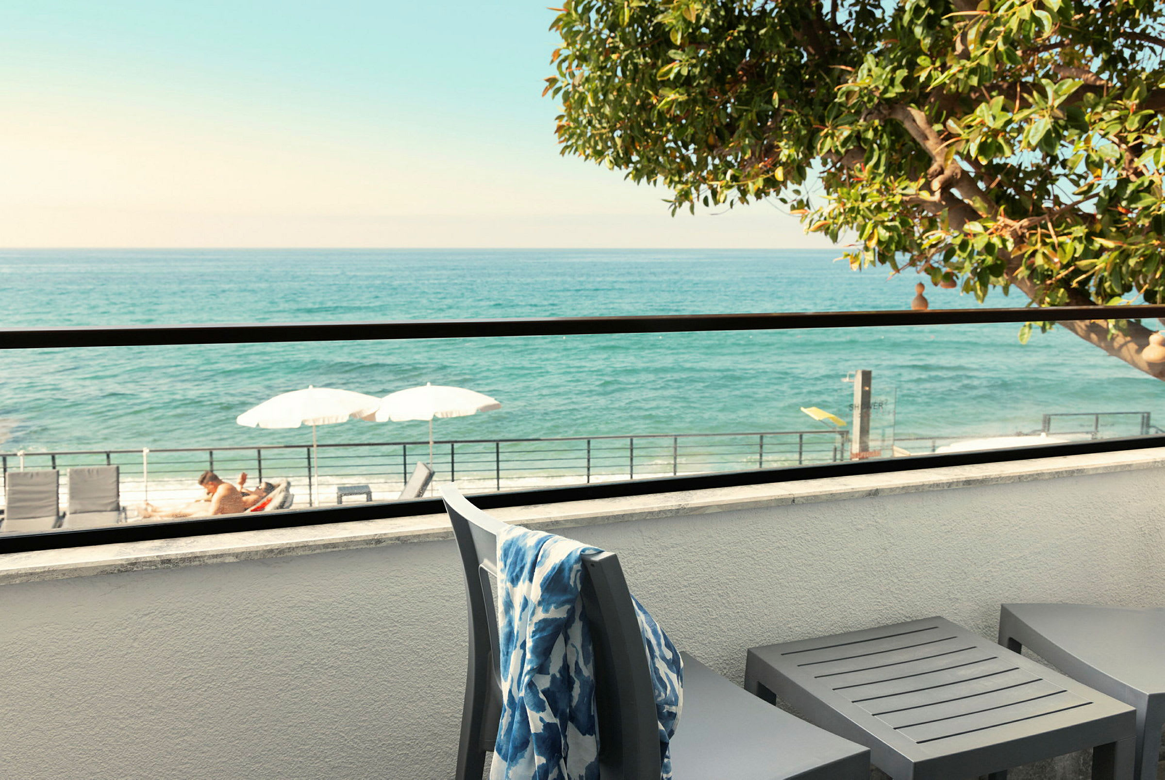 Terrasse med udsigt over havet, liggestole og parasoller er synlige. (AI-genereret tekst)