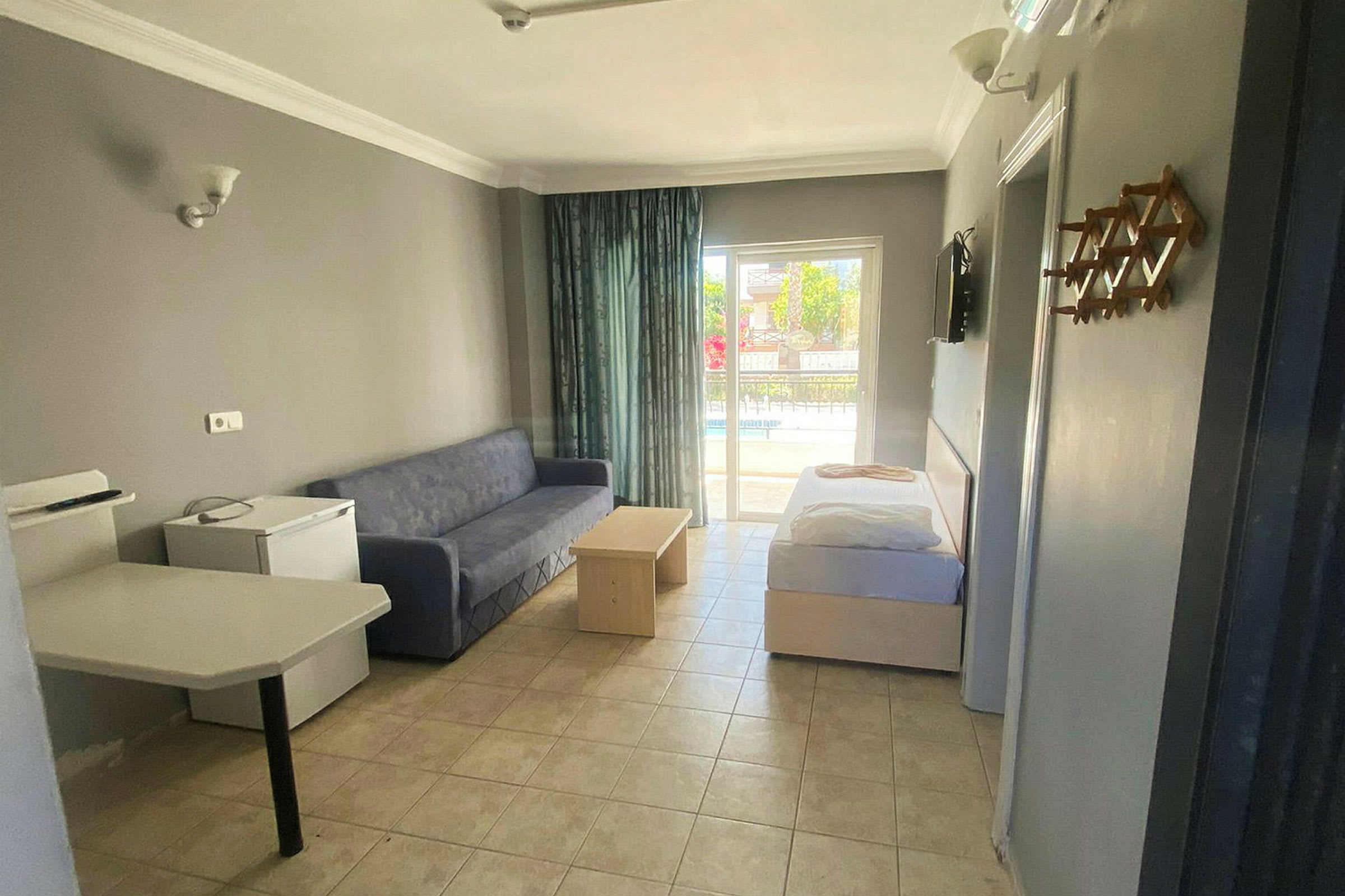 Et hotelværelse med sofa, bord og seng samt udsigt til en balkon. (AI-genereret tekst)