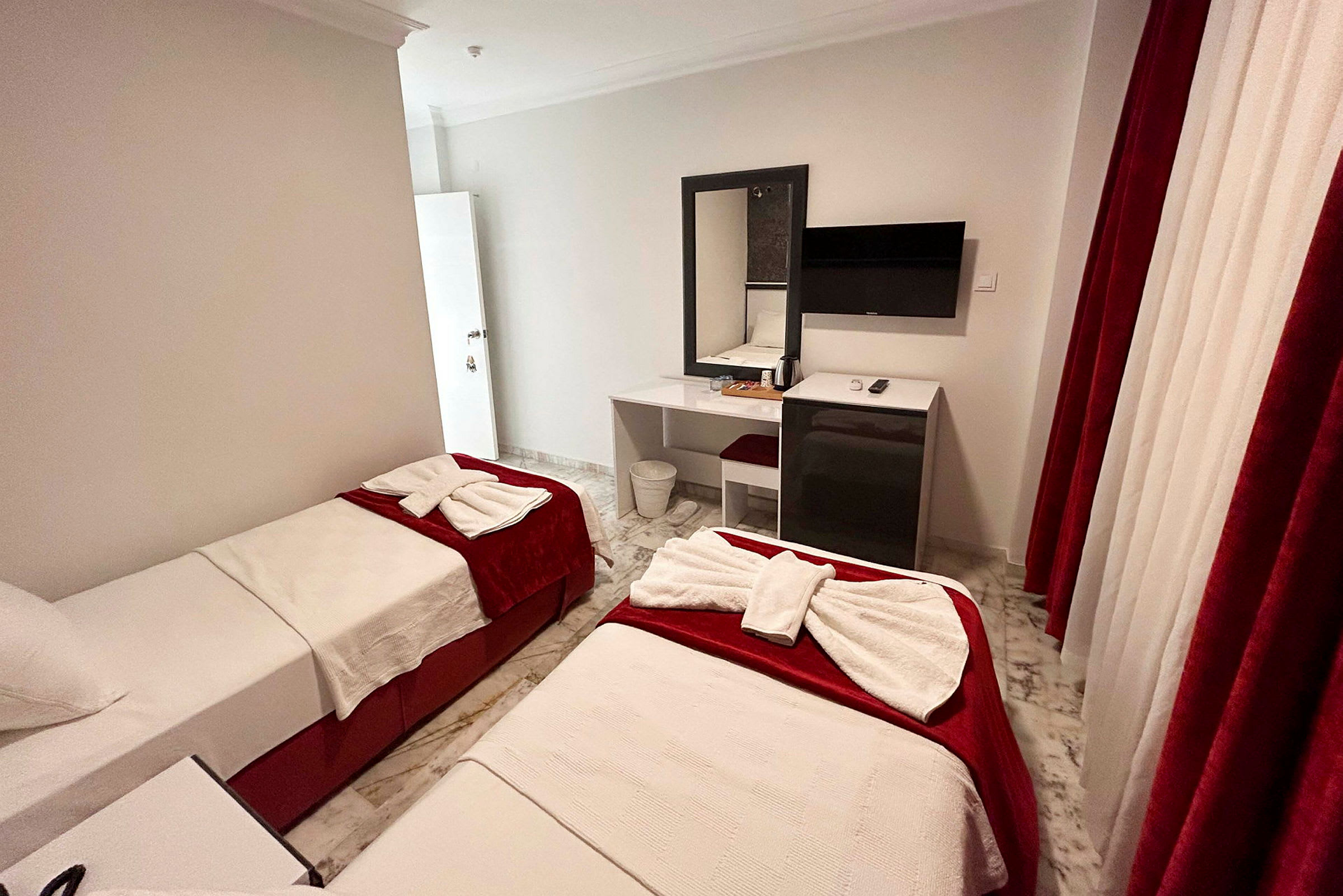 Hotelværelse med to enkeltsenge, skrivebord og TV. (AI-genereret tekst)
