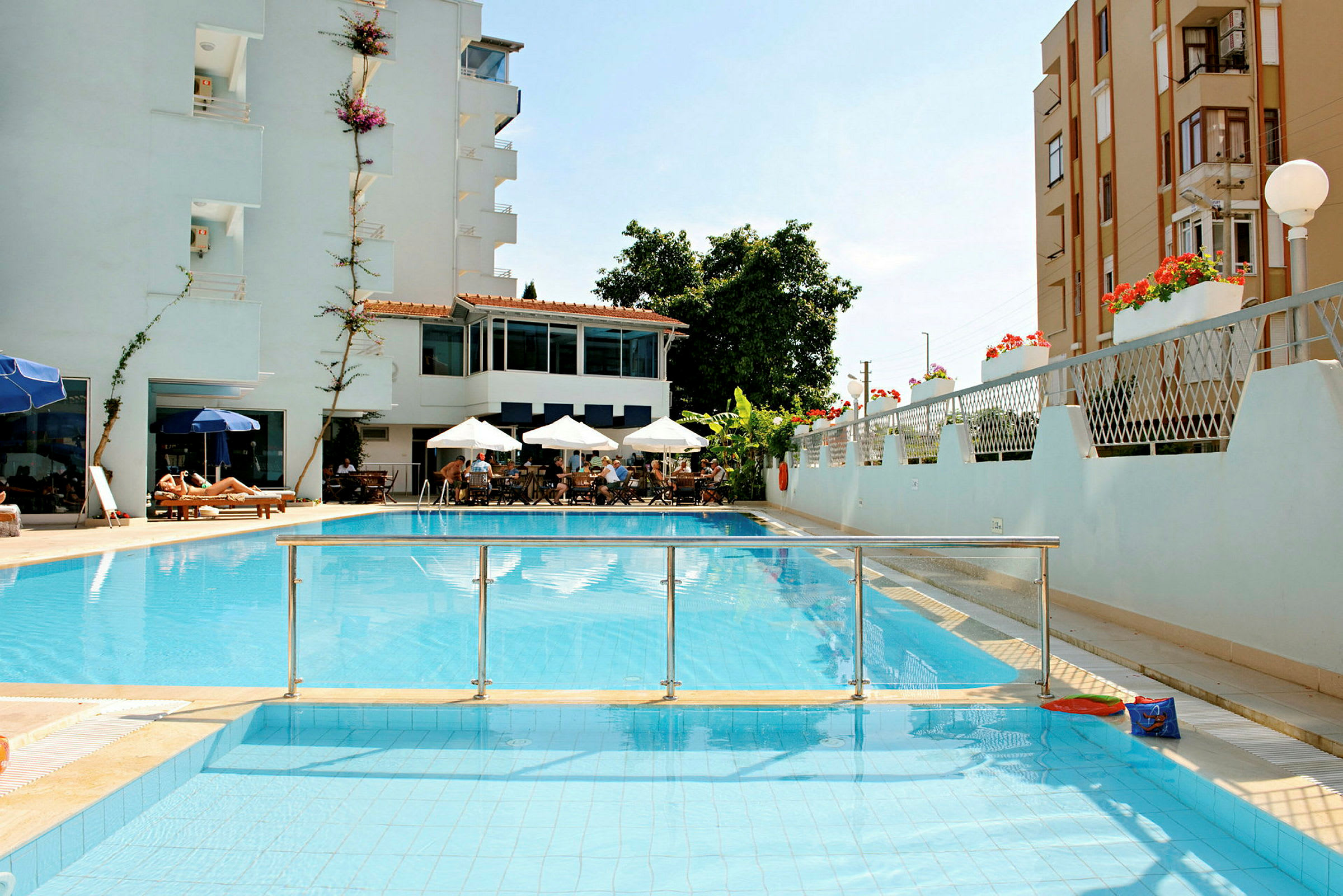 Et billede af et hotel med pool, siddeområde med parasoller og solsenge. (AI-genereret tekst)