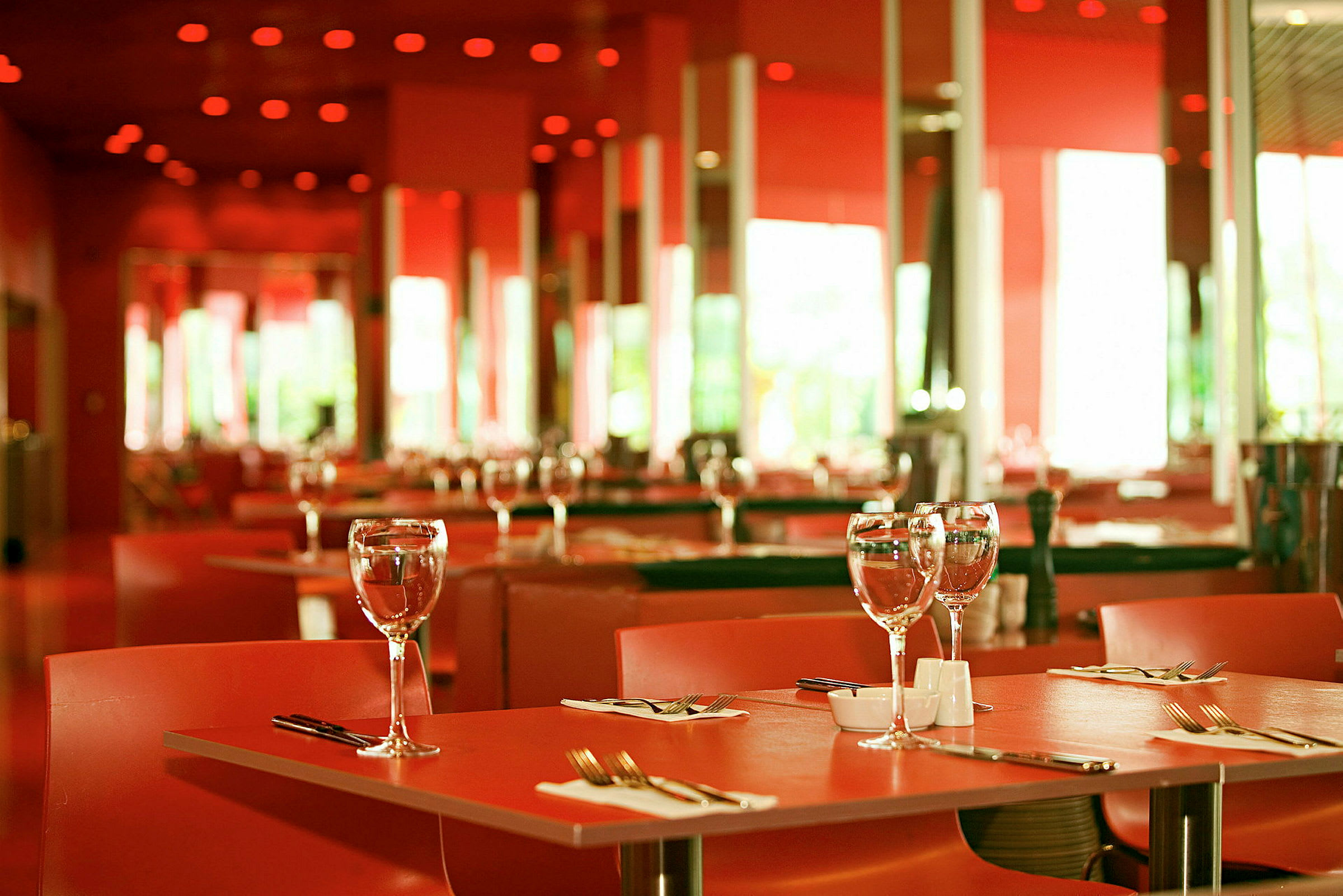 Et dækket bord i en elegant restaurant med rødt interiør. (AI-genereret tekst)