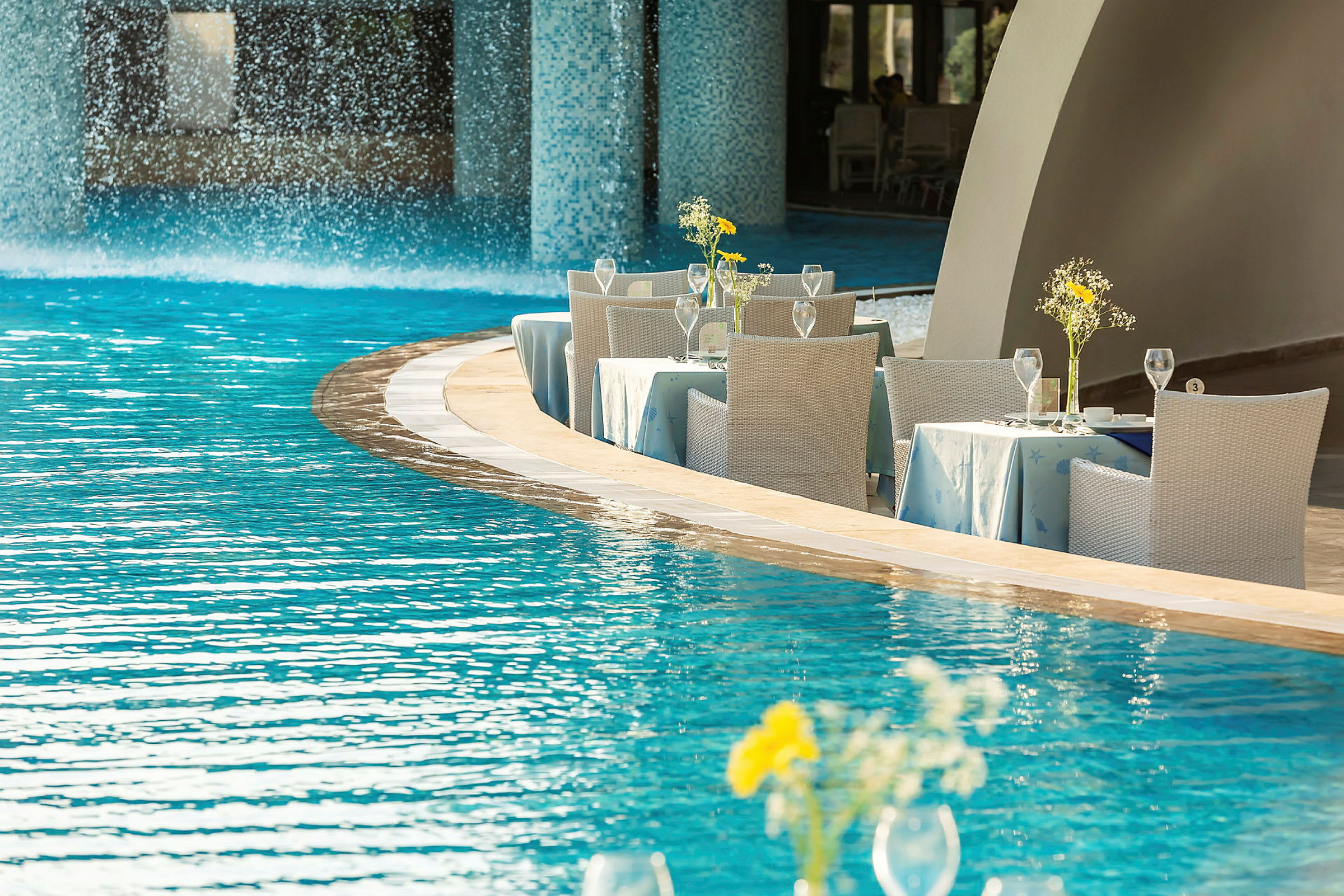 Udendørs terrasse med dækkede borde ved kanten af en pool. (AI-genereret tekst)