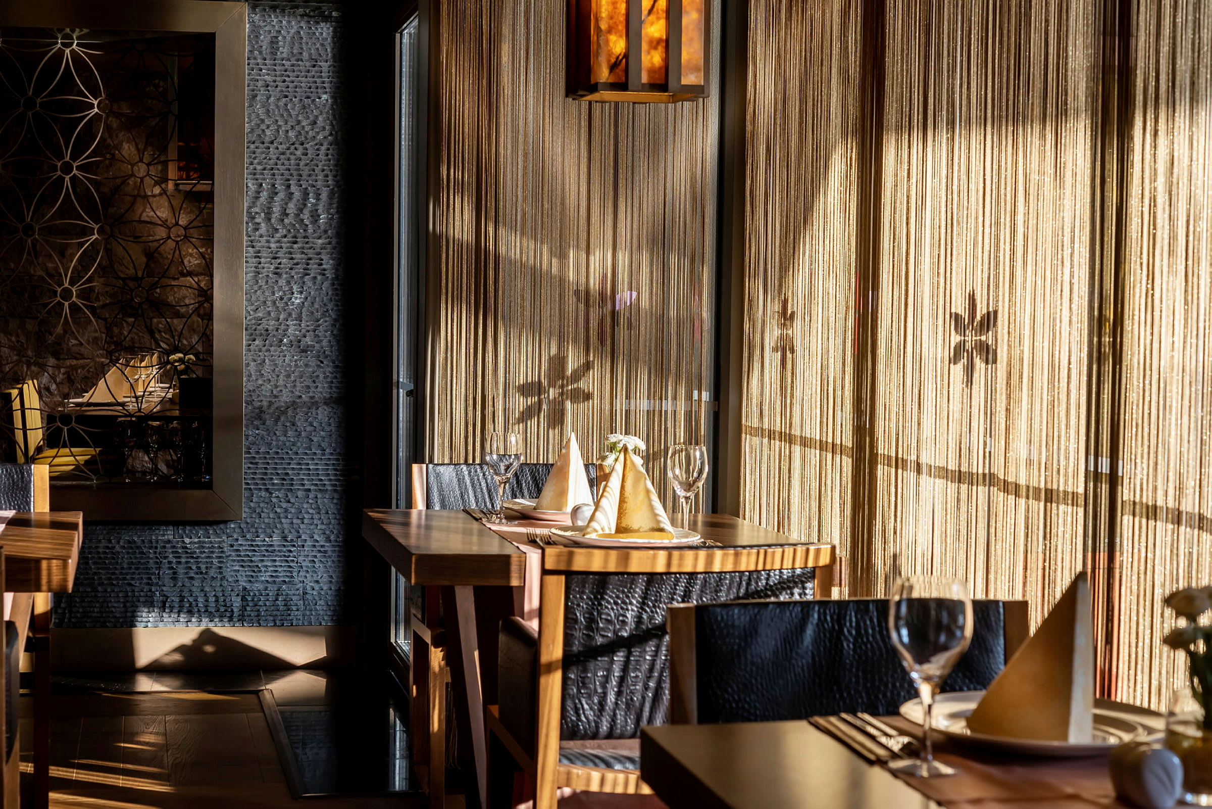 Interiør af en elegant restaurant med dækkede borde, lyssinslip og dekorative vægdetaljer. (AI-genereret tekst)