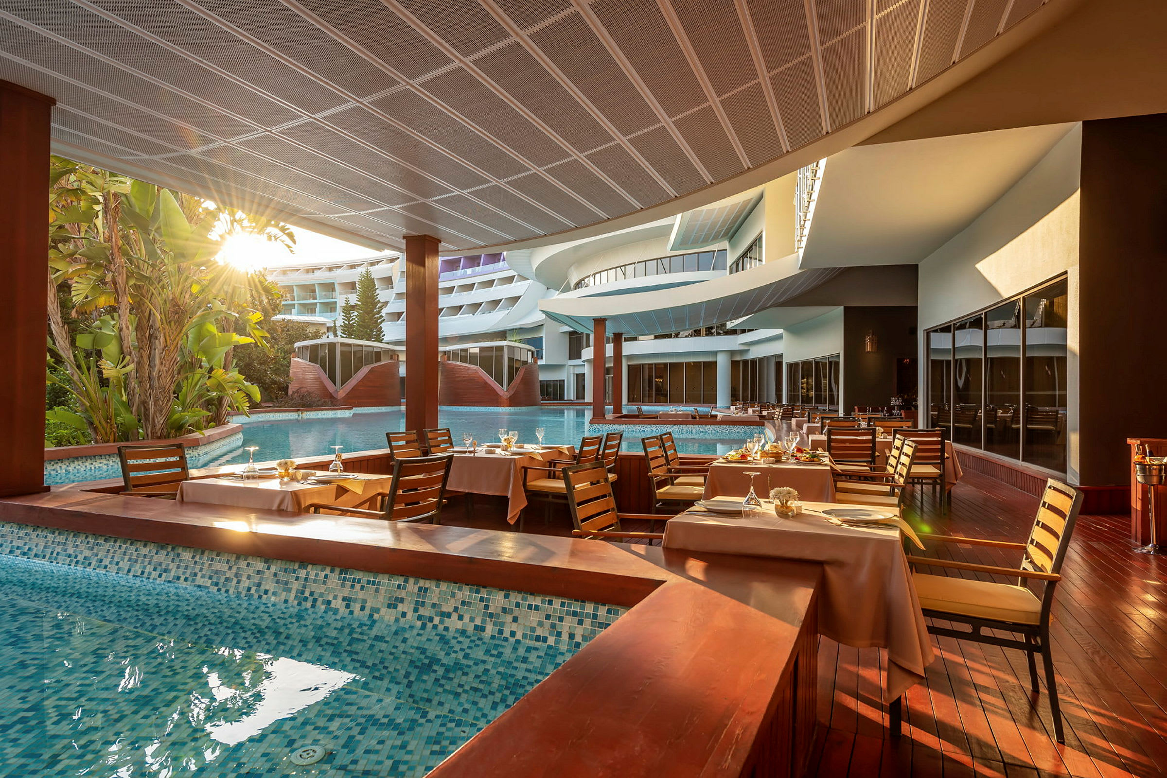 Hotelrestaurant ved en pool med dækkede borde. (AI-genereret tekst)